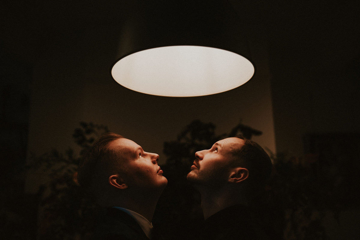 The Birdhouse197 founders standing close together in moody lighting on their Halloween wedding day