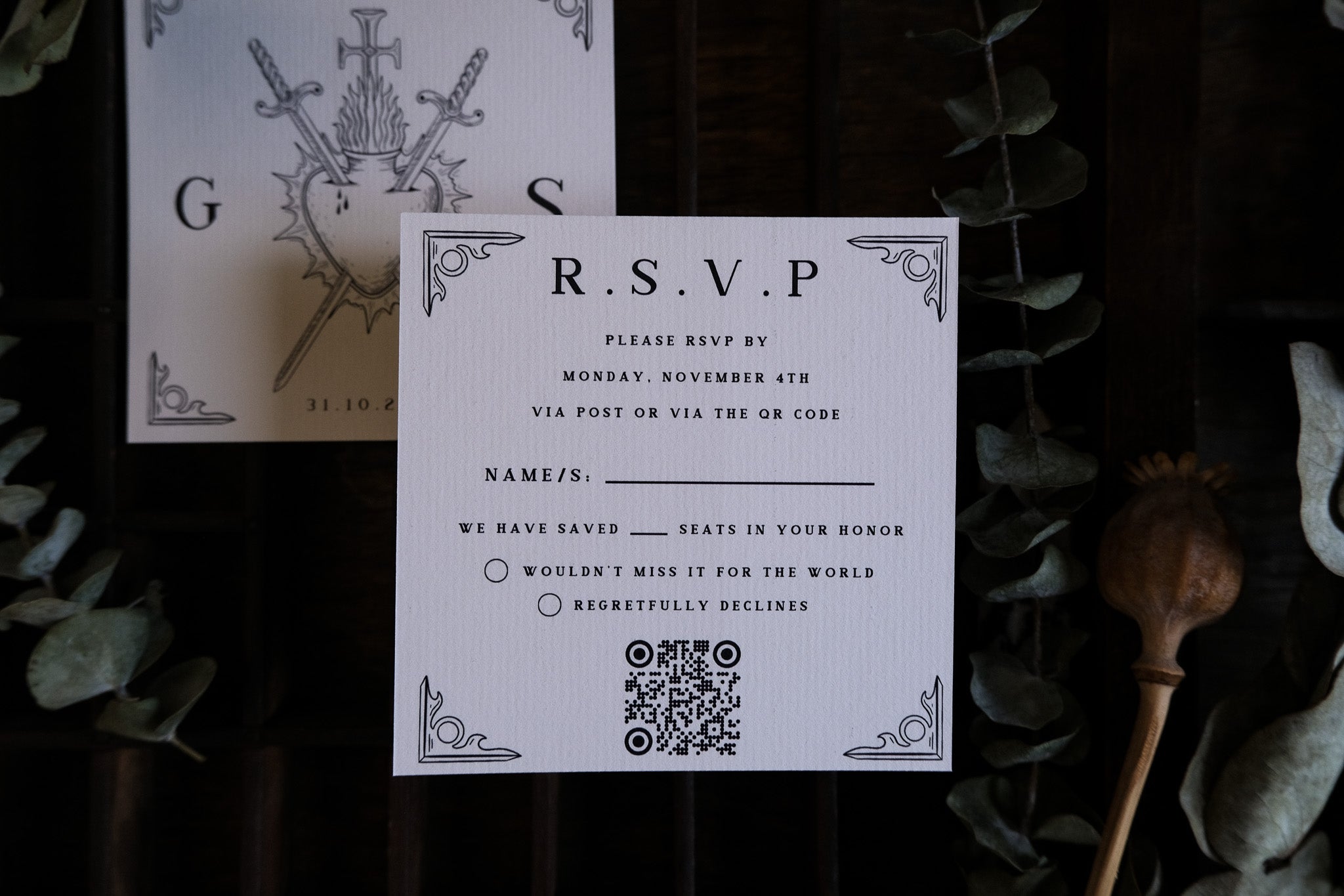 Luxury UK wedding RSVP card with dramatic black gothic motifs, vintage accents, greenery details, and a modern QR code.