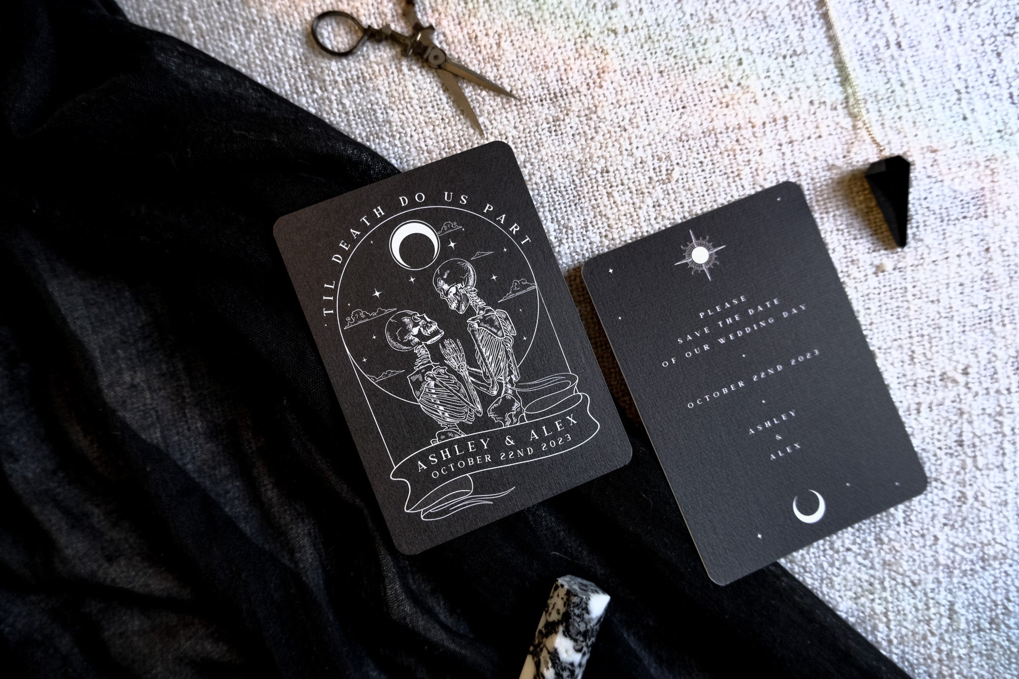 Luxury gothic wedding stationery save the date with a celestial skeleton couple, moon, stars, and crystals on textured premium paper.