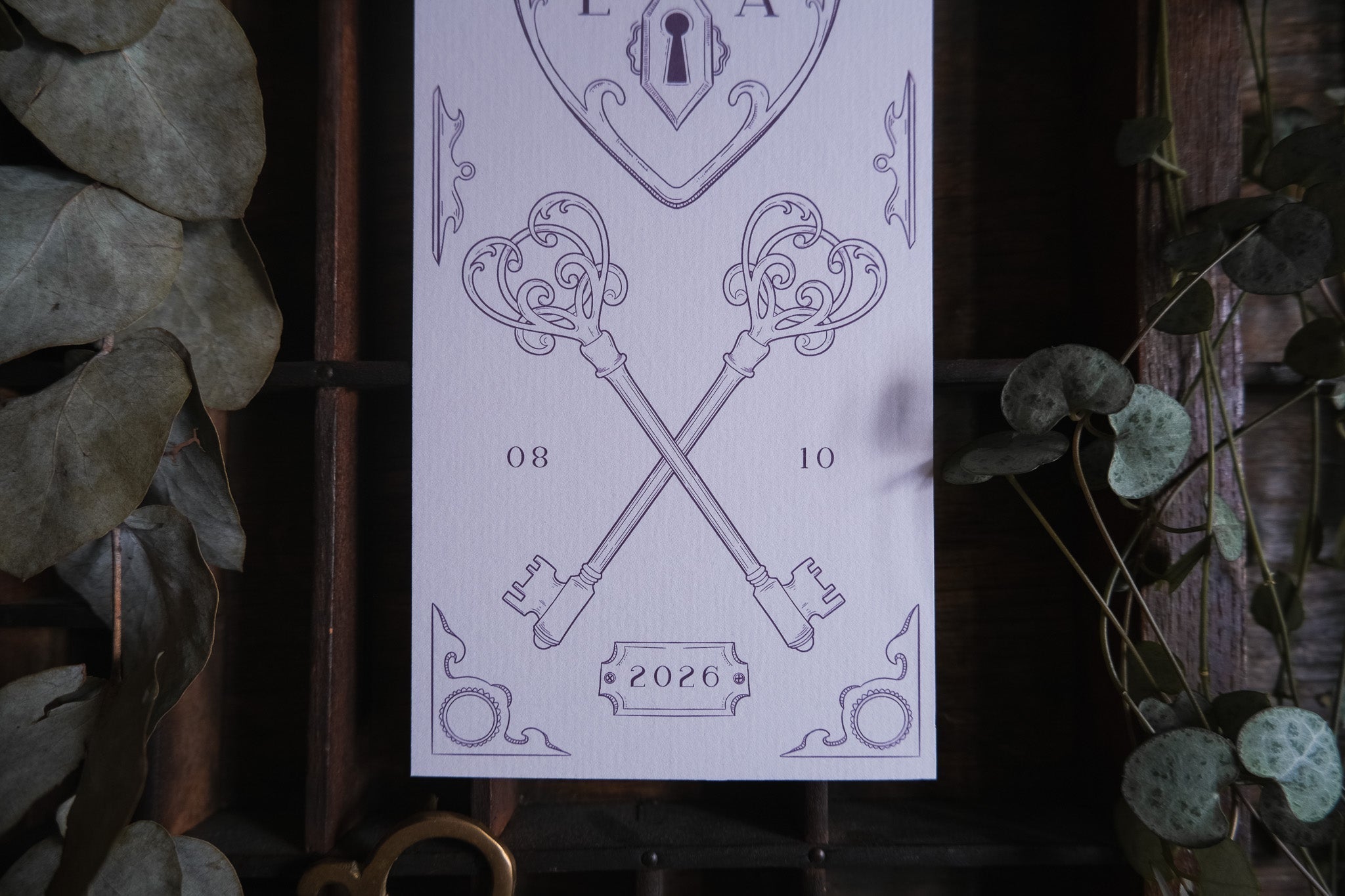 Luxury UK wedding stationery save the date with vintage gothic keys, heart padlock, floral detail, and dramatic dried leaf accents.