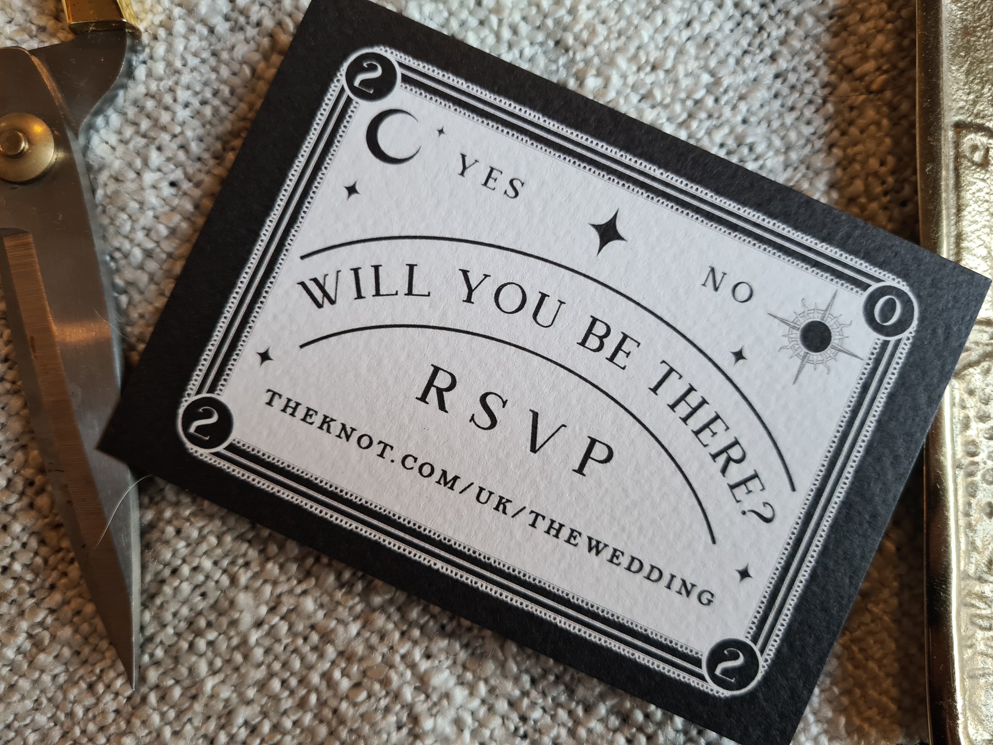 Ouija-inspired RSVP card on textured surface with vintage design elements.