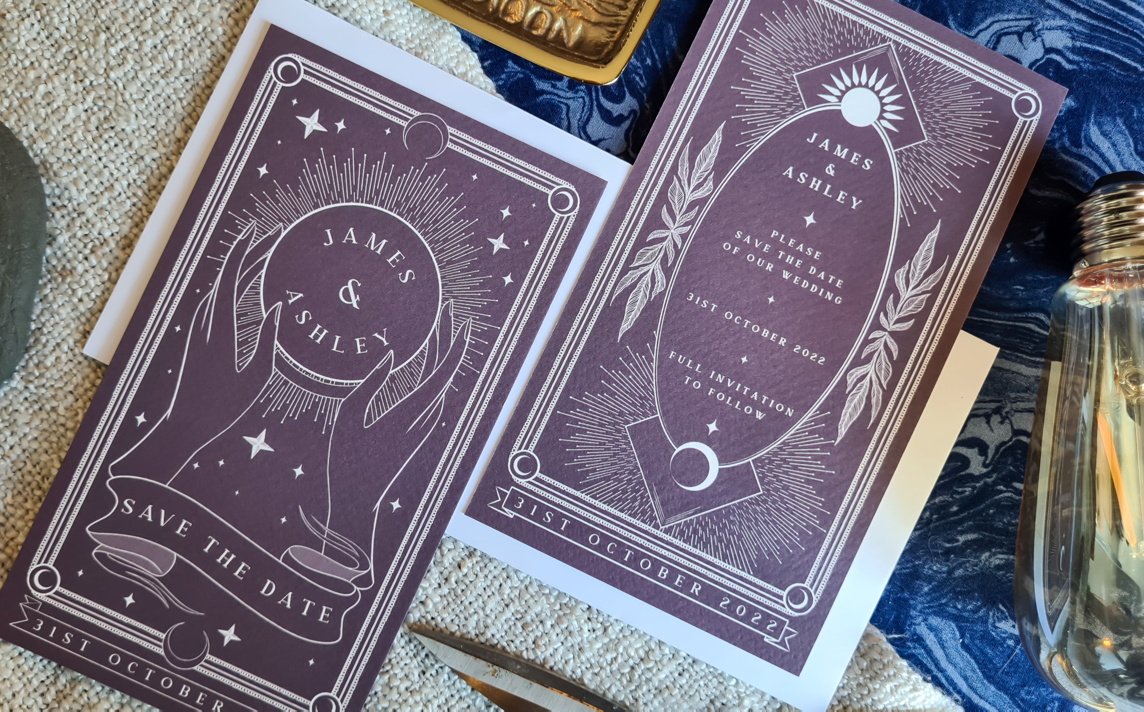 Luxury UK wedding stationery set with dramatic purple celestial and botanical design, on patterned fabric with romantic accents.