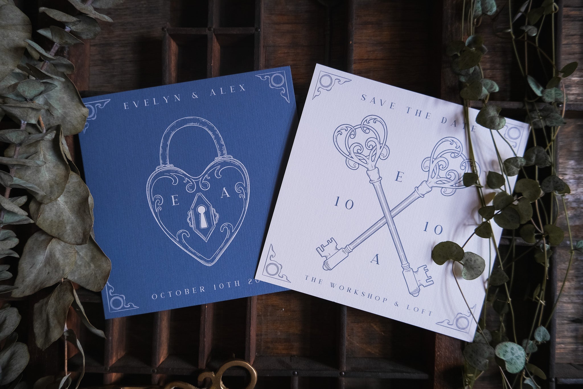 Luxury vintage wedding stationery with gothic Victorian-inspired lock and key motifs, set on rustic wood and framed by dried leaves.