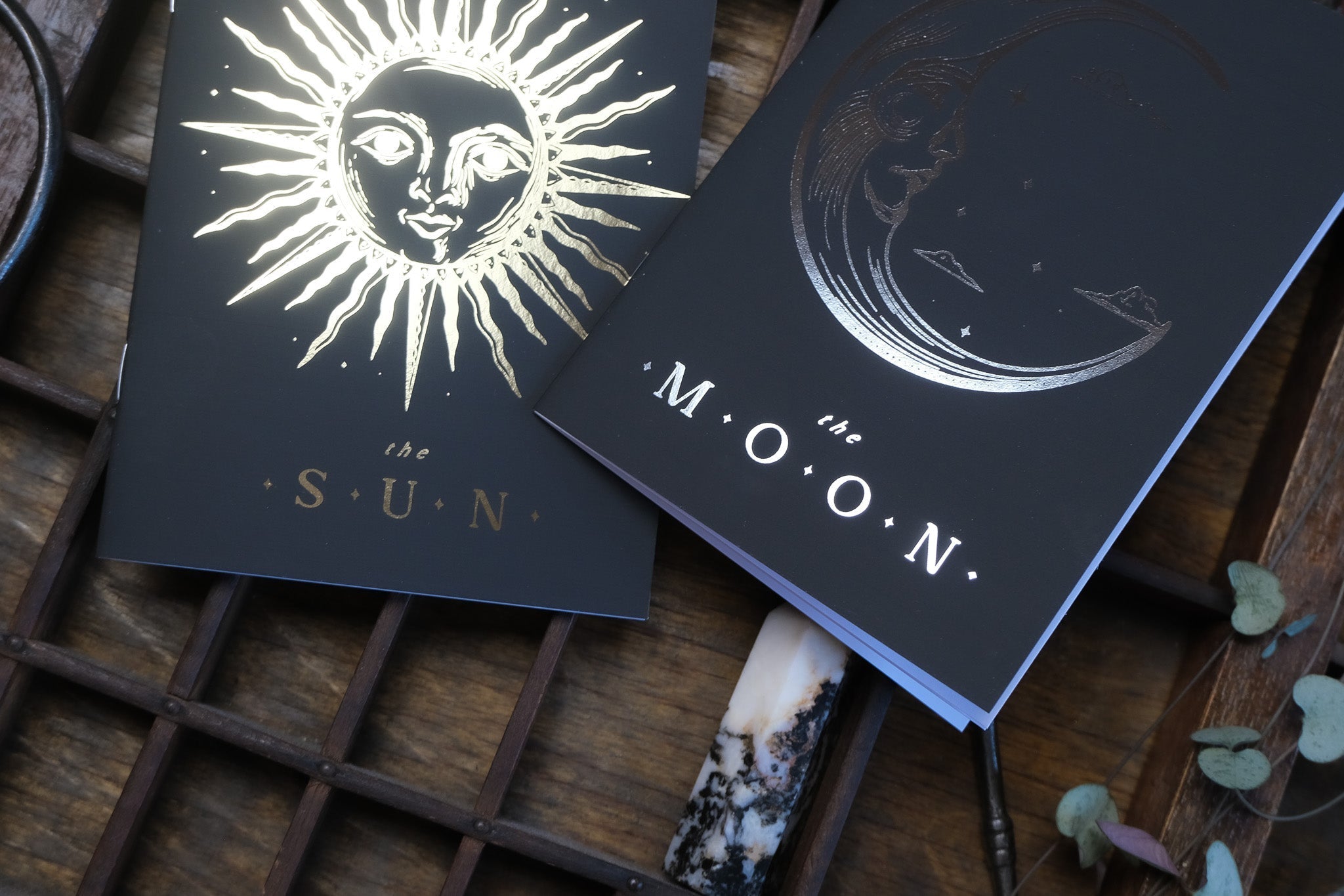 Luxury celestial wedding stationery vow books with dramatic gold and silver foil, gothic sun and moon motifs, crystal, dried leaves.