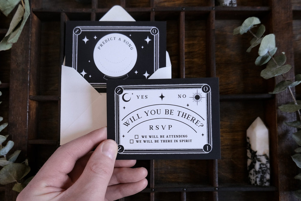 Ouija-inspired RSVP card with gothic spirit board design and white envelope, perfect for occult-themed weddings