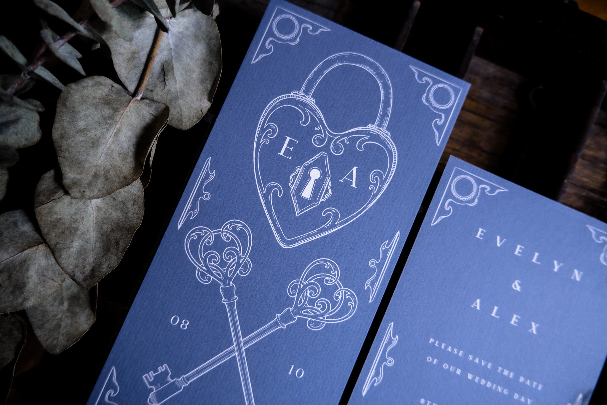 Luxury blue wedding stationery with heart-shaped lock and keys, featuring vintage-inspired design. Eucalyptus accents add romance.