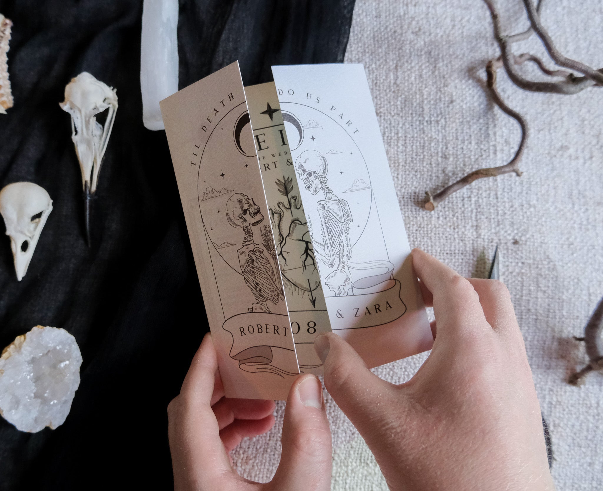 Skeleton Lovers & Bleeding Heart 'Til Death Do Us Part' gatefold wedding invitation with intricate design, foldable card shown with white envelopes, 250 GSM matte textured finish.