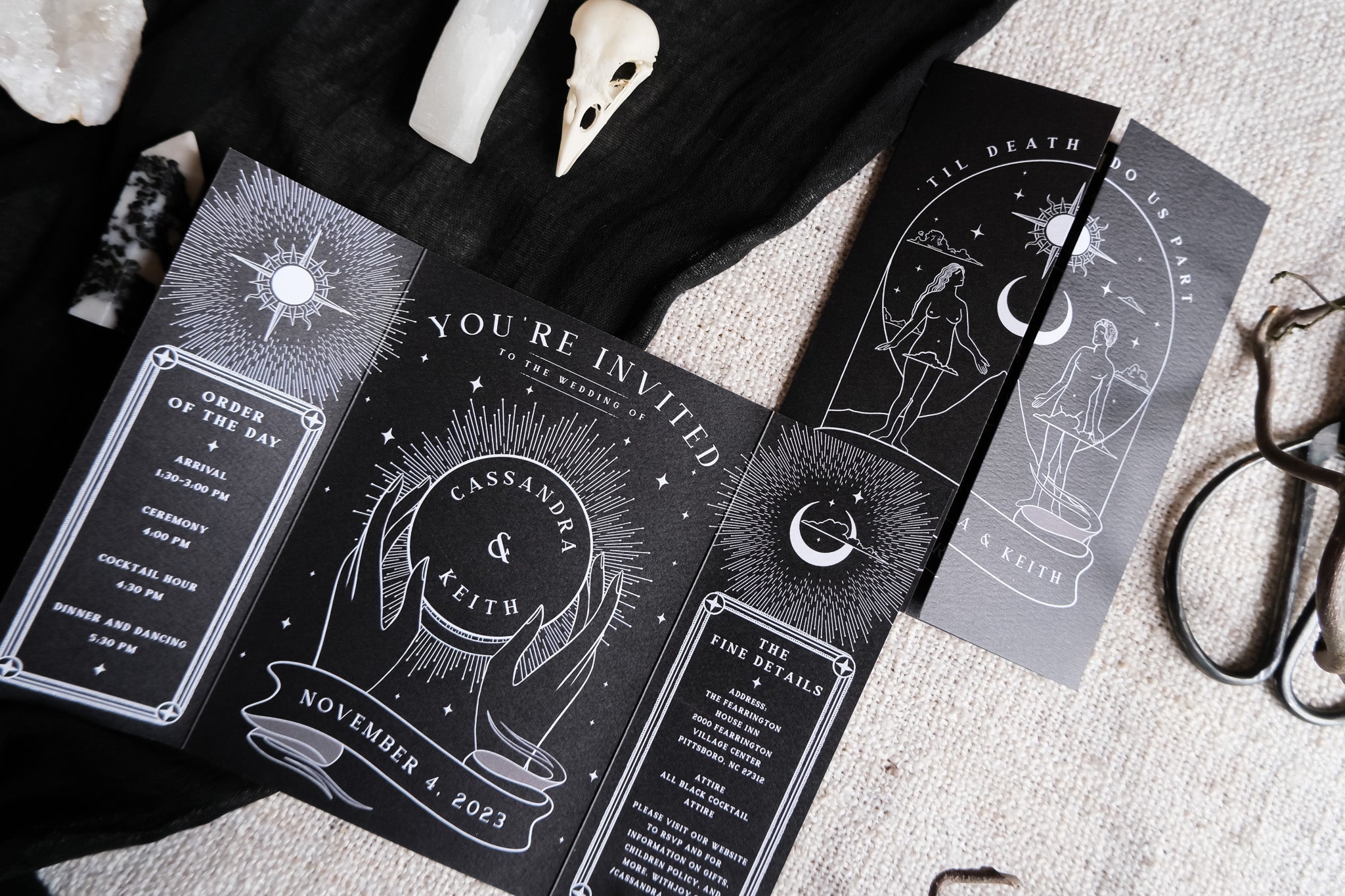 'Lovers Tarot Card' gatefold wedding invitation on a black cloth with skull and scissors decorations.