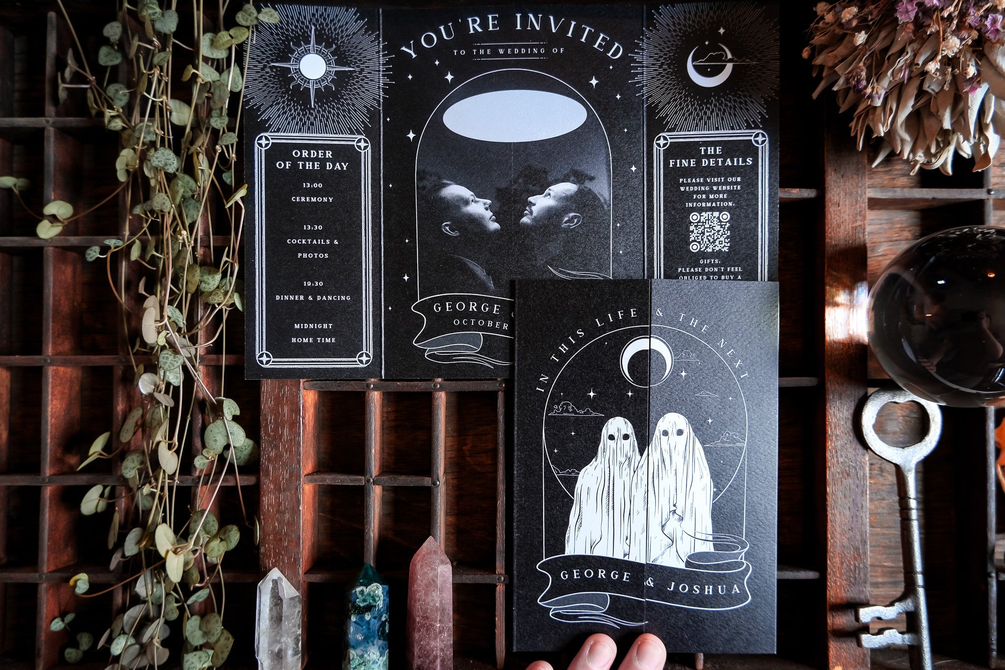 Ghosts Gatefold Wedding Invitation with gothic design and white envelopes on display, featuring illustrated ghost figures, customizable in color or gradient, printed on 250 GSM matte textured card.