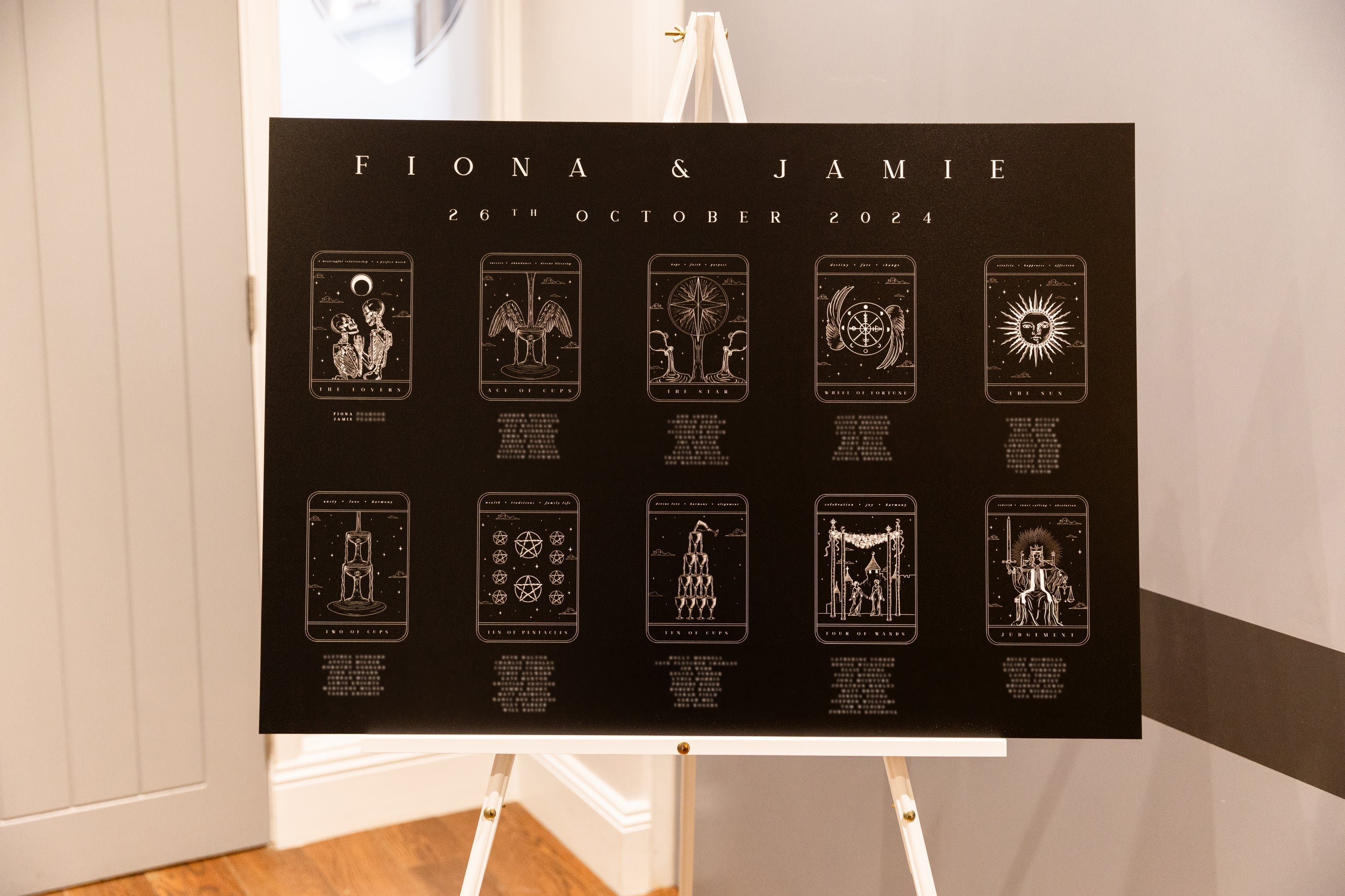 Tarot card wedding seating plan on easel with personalized details and various tarot designs.