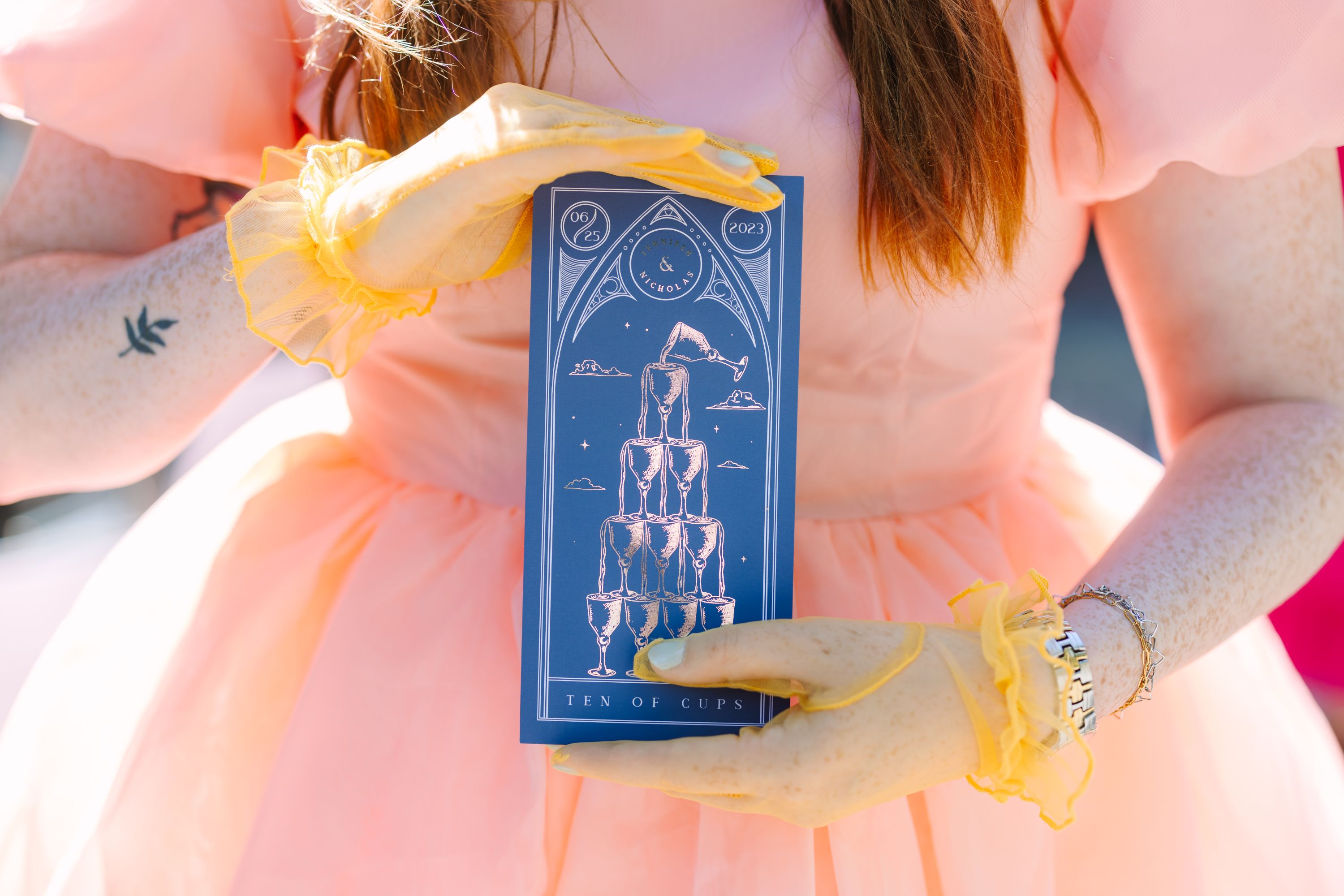 Cups' Foiled Tarot Card Save the Dates being held by person in peach dress.
