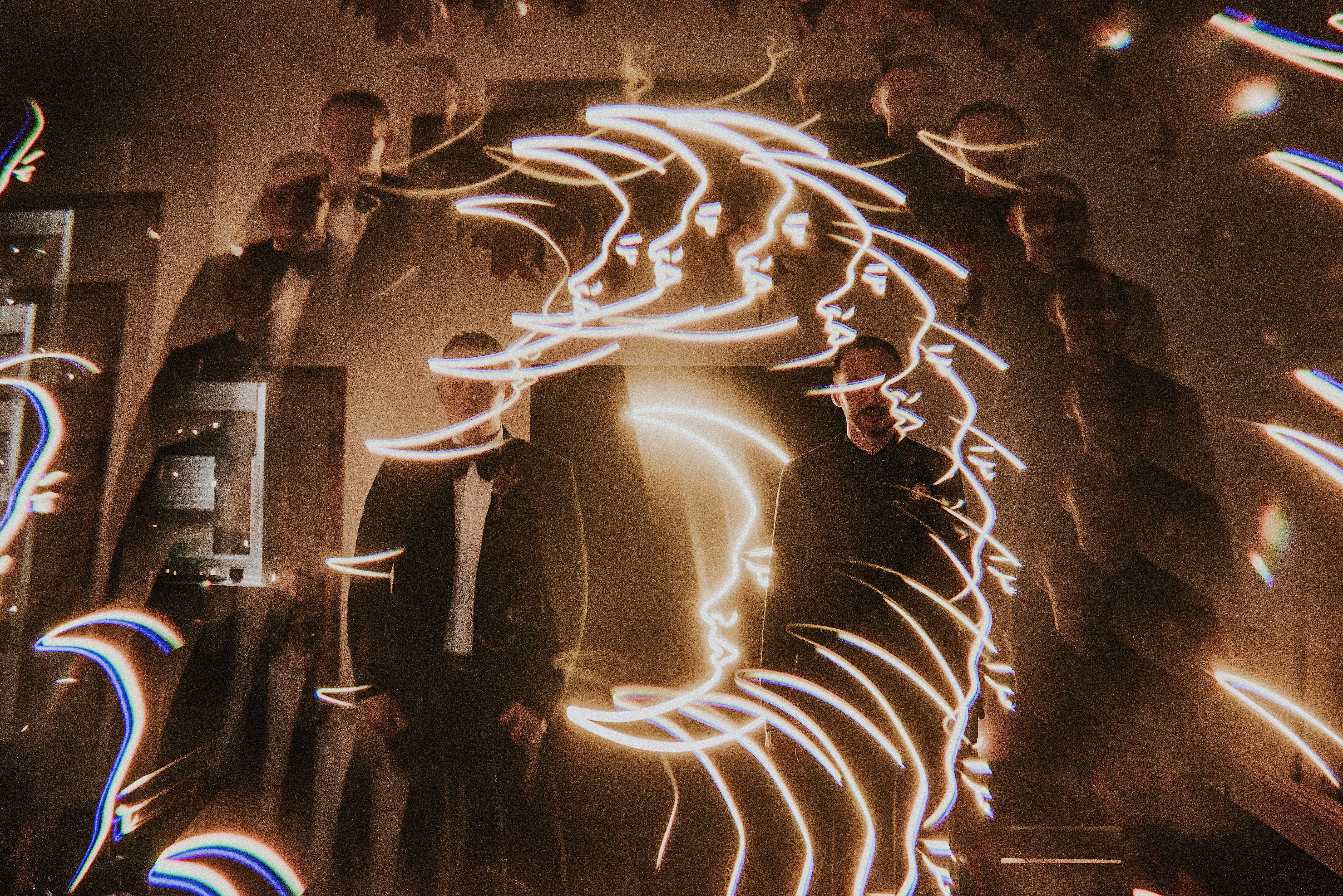 People in formal attire with light art projection on a wall - Halloween Wedding Shot