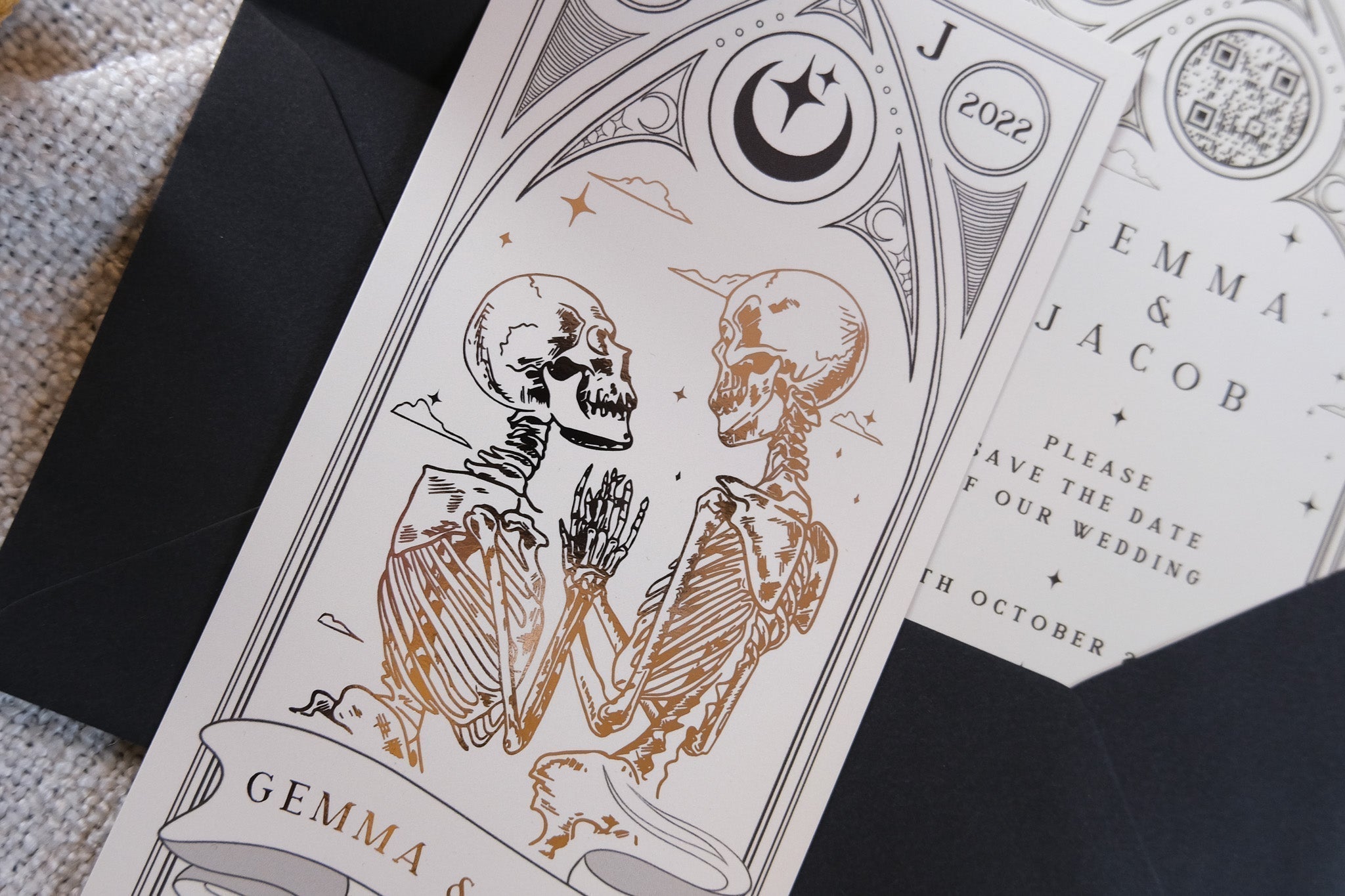 Gothic skeleton couple foiled save the date card titled The Lovers Til Death Do Us Part on velvet soft-touch card