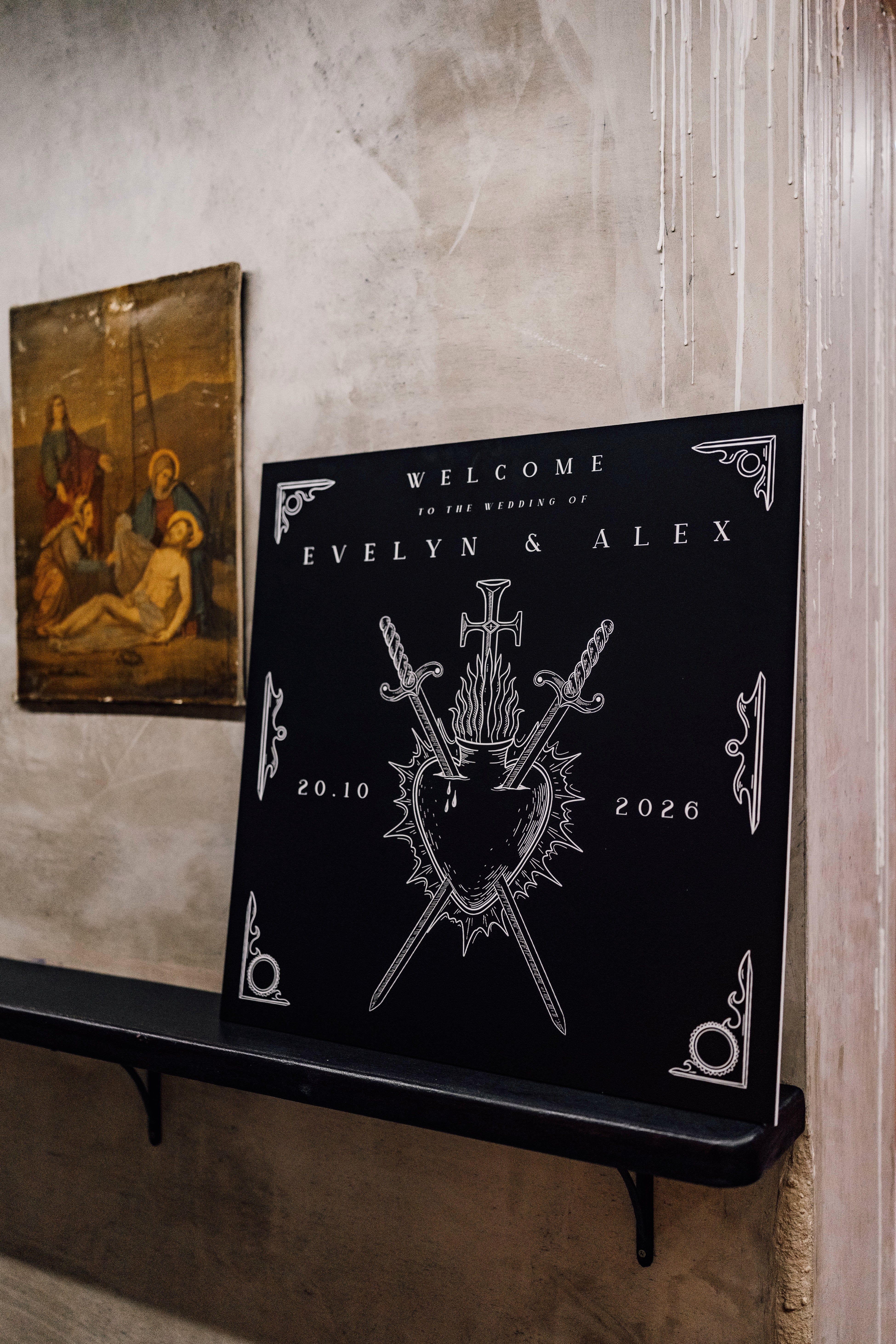 Luxury gothic personalised black wedding welcome board with white mystical sword, heart, and flame art, styled beside vintage decor.