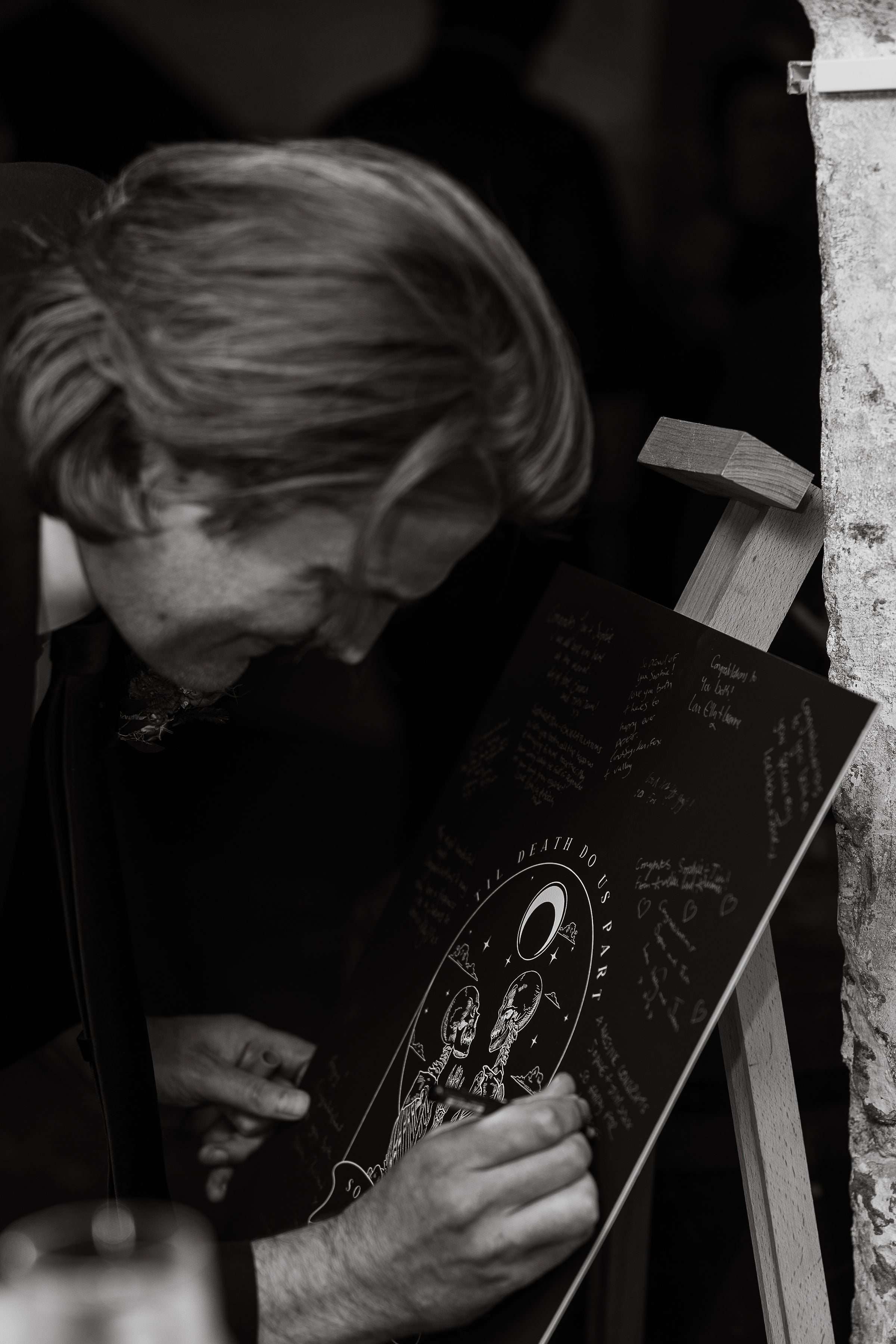 A luxury black celestial wedding sign on easel, featuring mystical illustrations and handwritten notes; dramatic, vintage UK setting.
