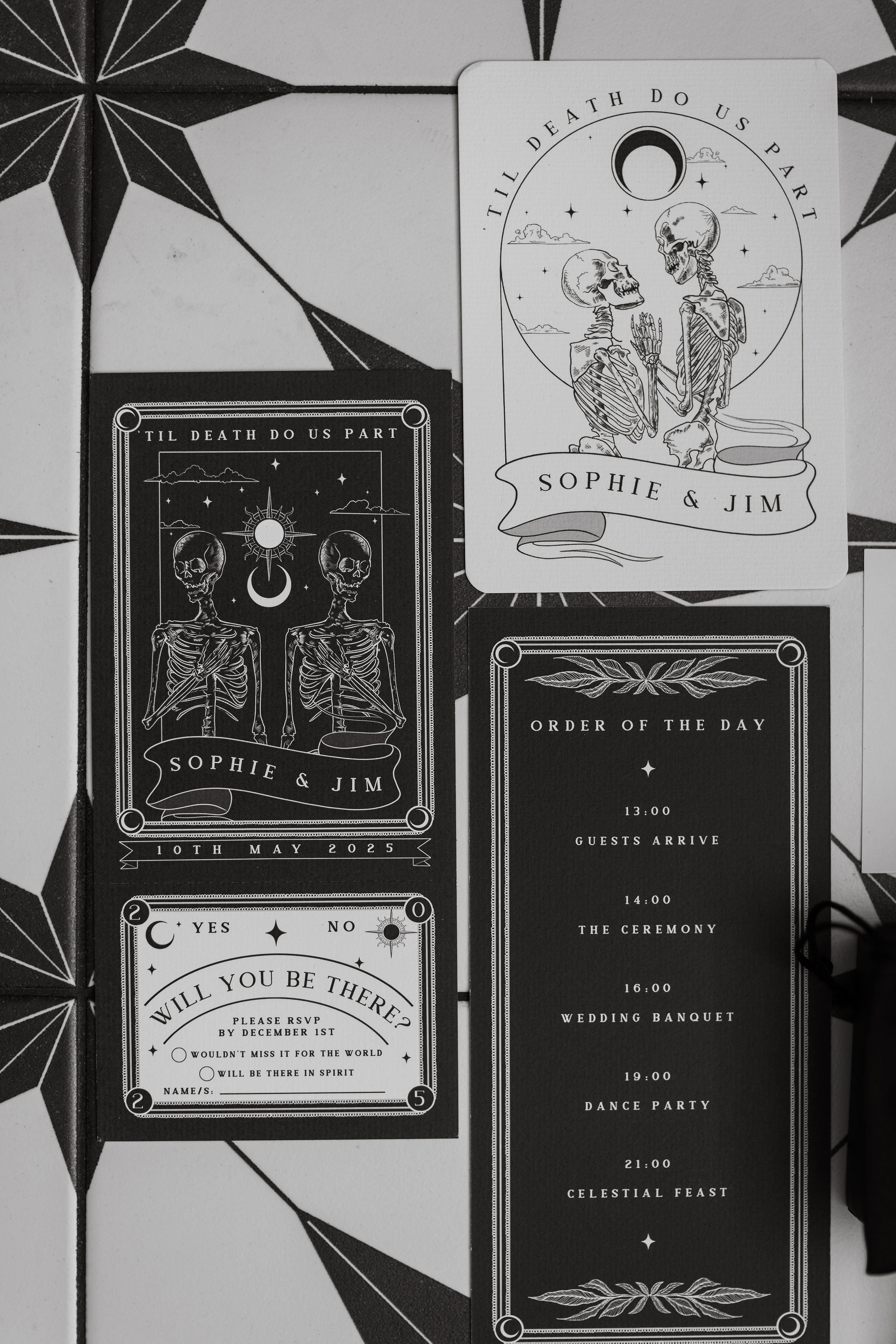 Luxury black and white gothic wedding stationery with skeleton motifs, dramatic vintage style, on a patterned surface.