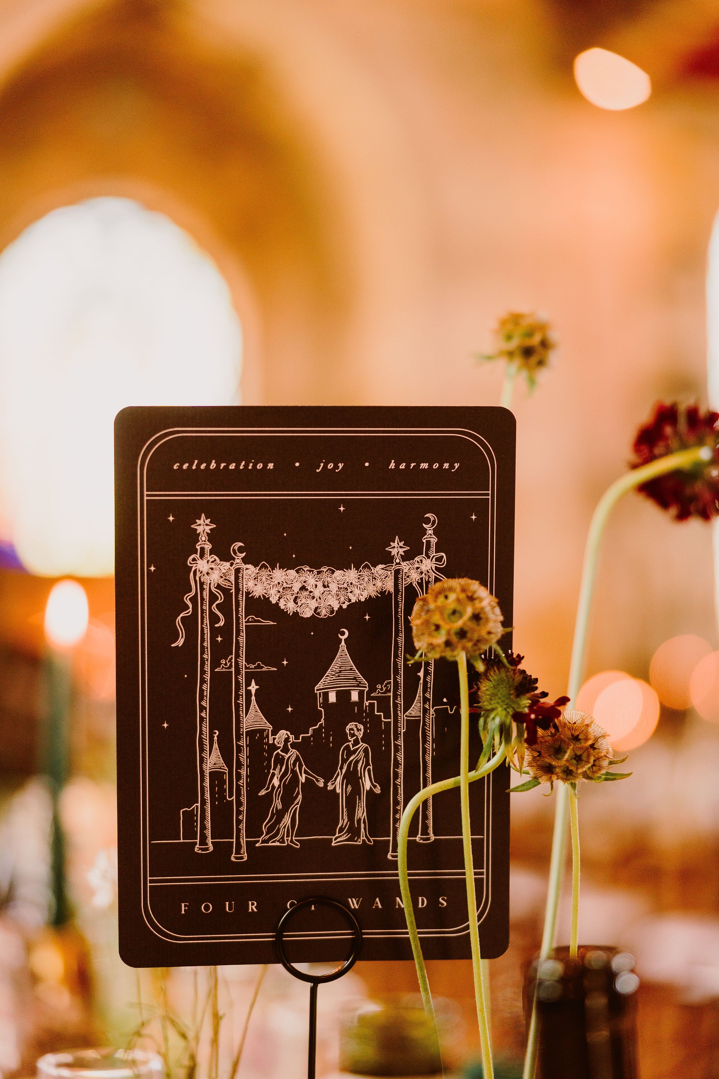Luxury tarot-inspired wedding stationery features a mystical, romantic design with warm lights and blurred florals on the table.