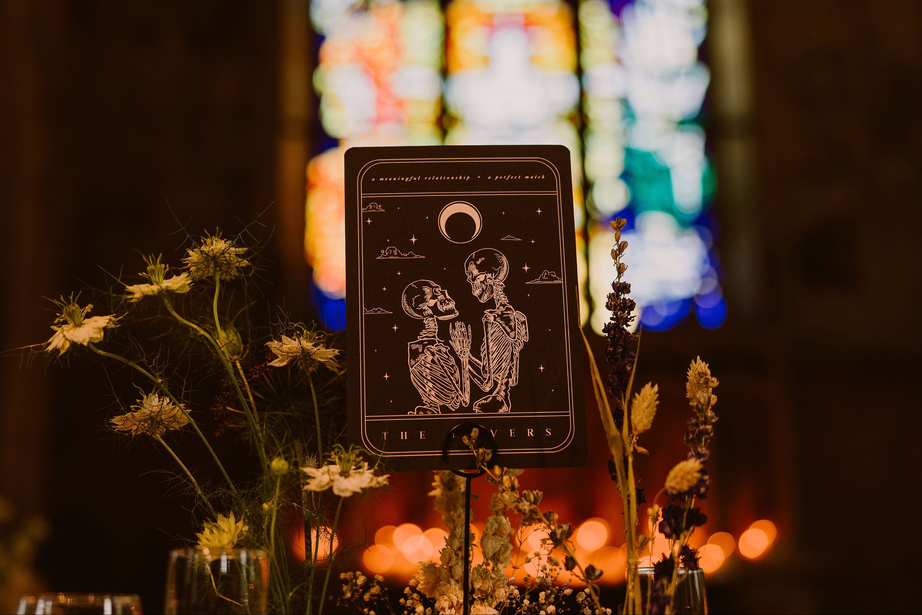 Luxury UK wedding stationery card with a gothic celestial design—embracing skeletons, moon, wildflowers, and vintage glow.