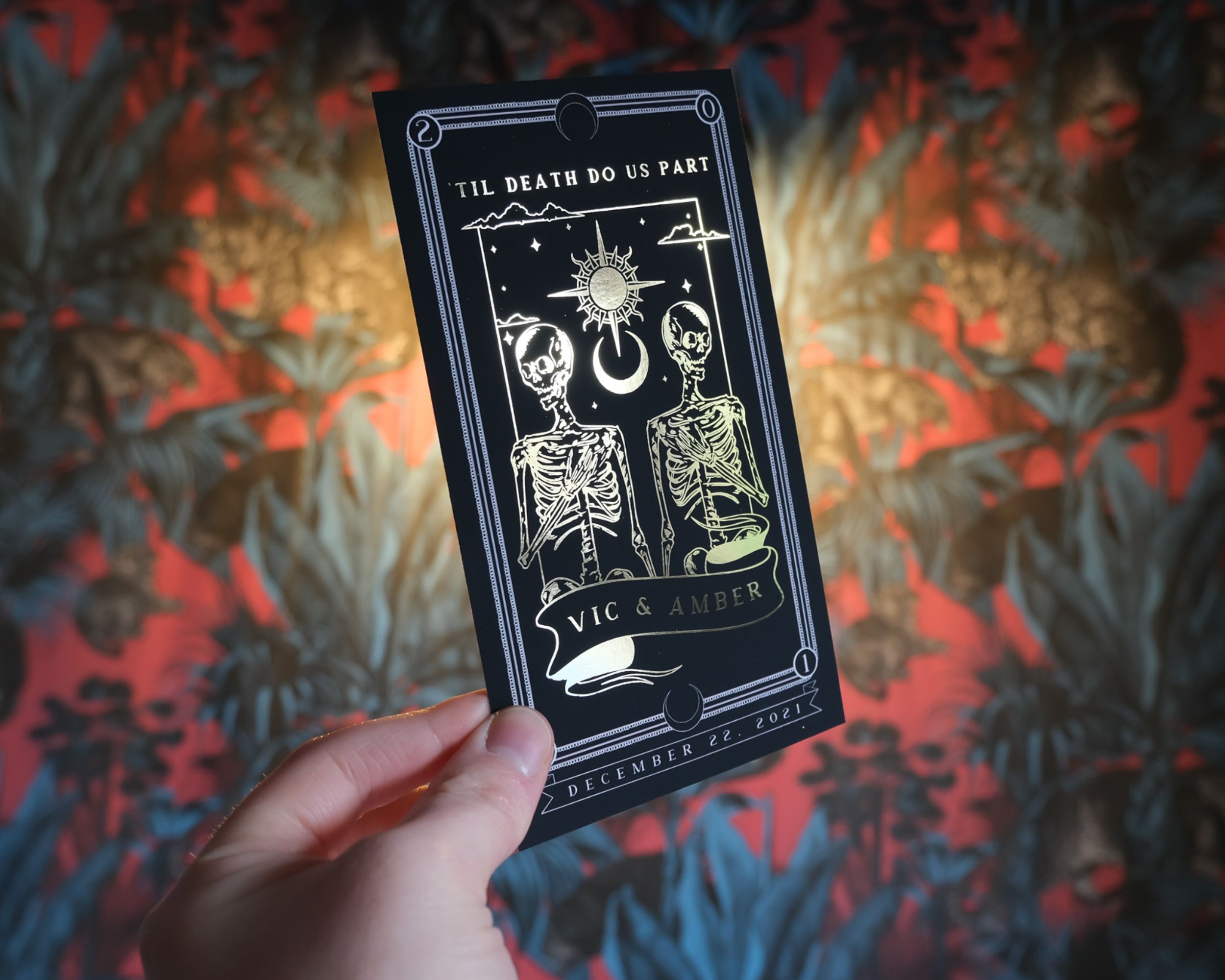 'Til Death Do Us Part' foiled save the date card with gothic tarot design, intricate foil detailing, held in hand.