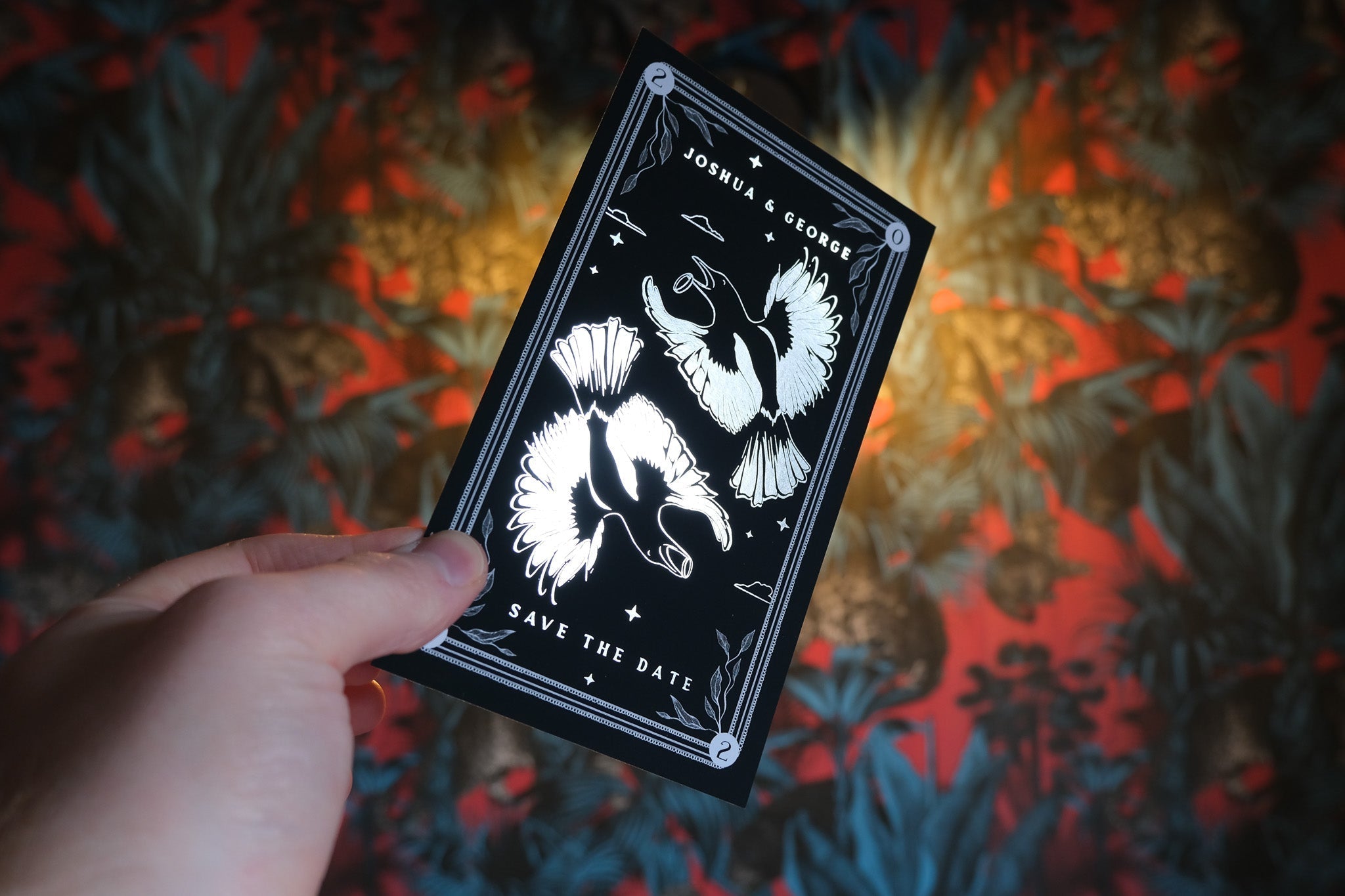 Magpie foiled tarot card save the date held against colorful background.