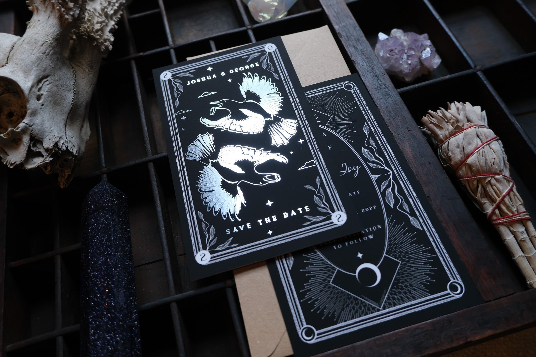 Tarot card save the date with magpie design and white foil accents.