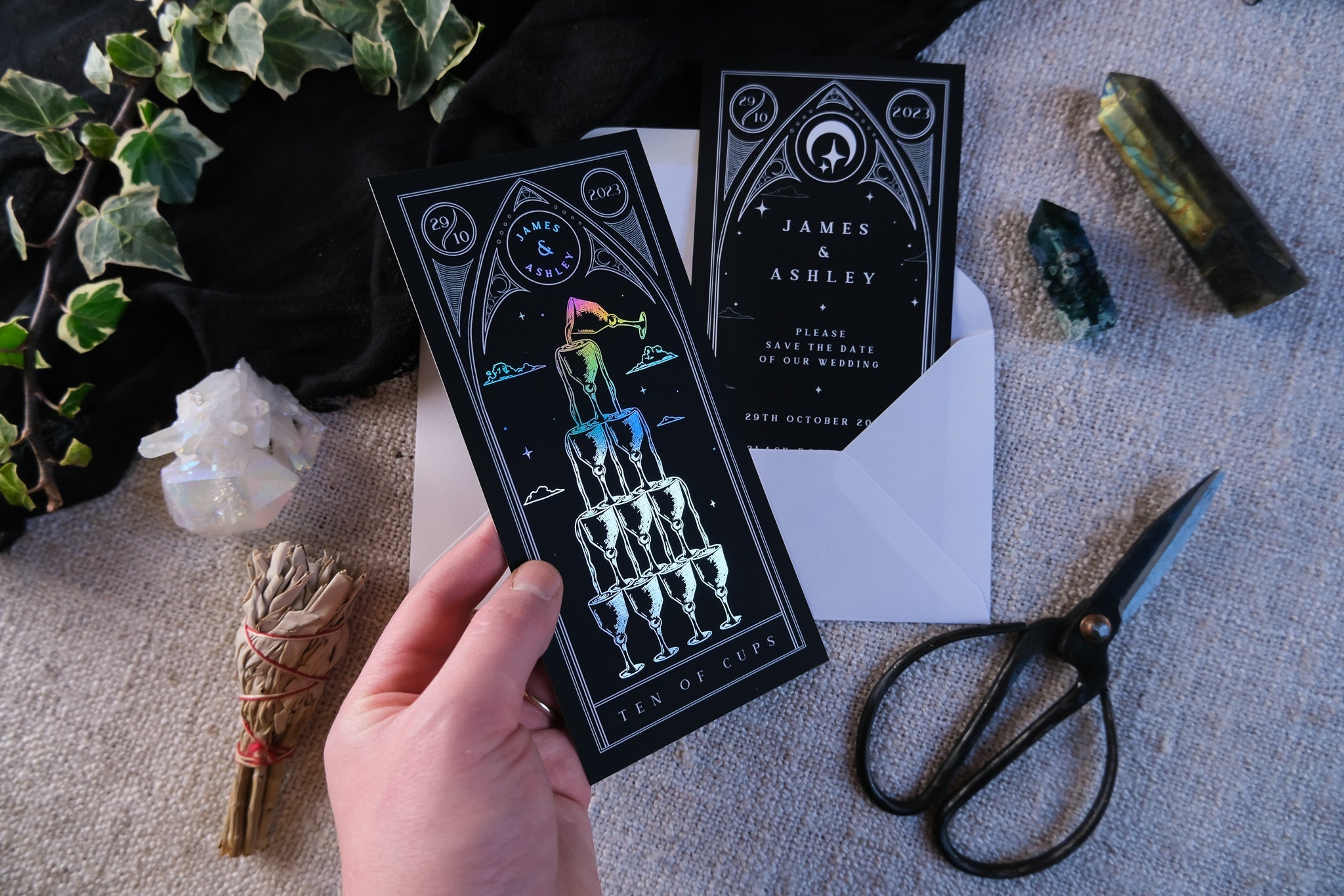 Ten of Cups foiled tarot card save the dates with white envelopes and natural elements.