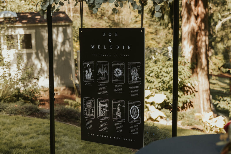 Luxury personalised wedding seating plan with a dramatic black tarot-inspired design, displayed in a mystical UK garden setting.