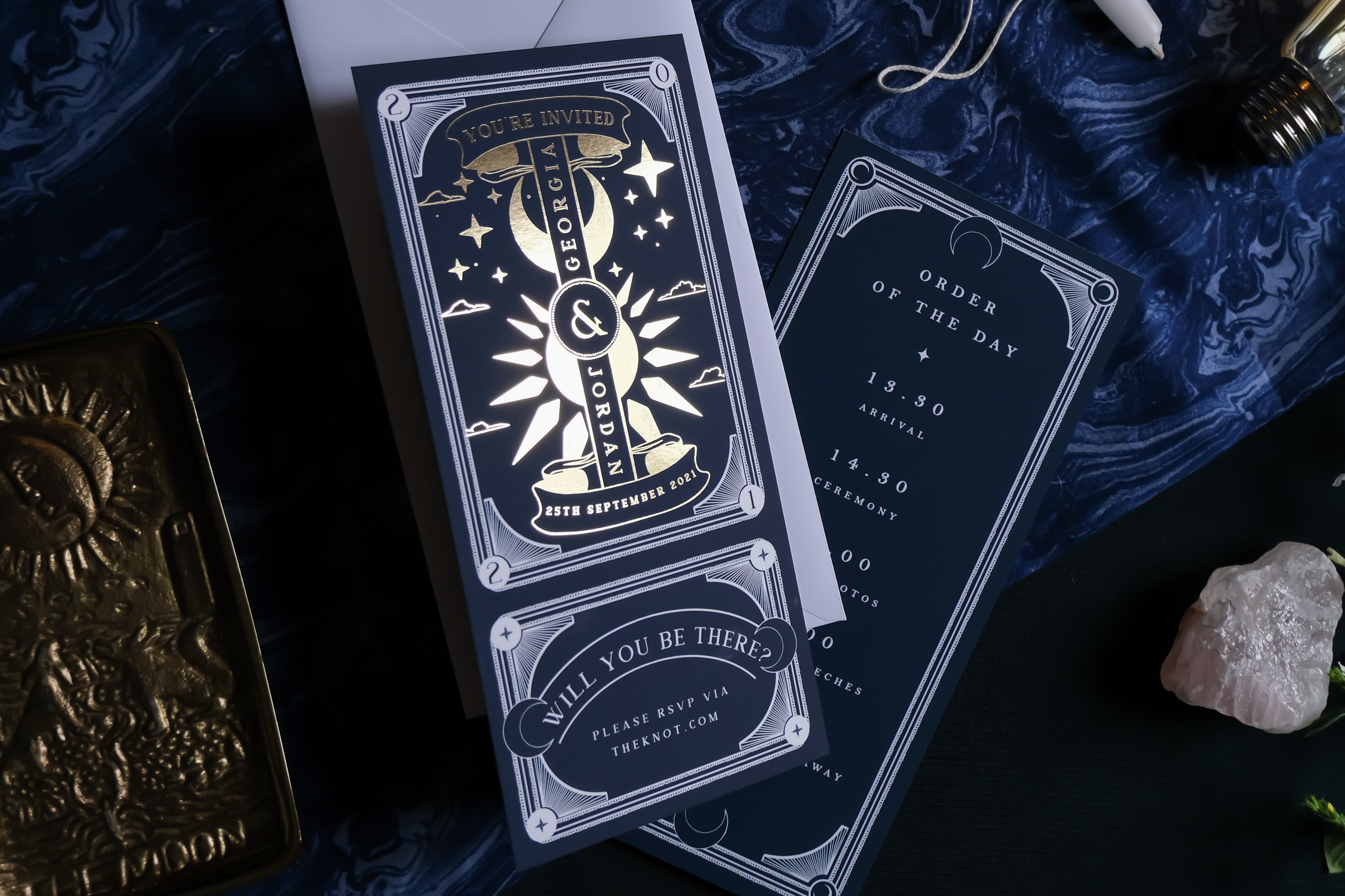 Celestial luxury wedding stationery suite with foiled, mystical tarot-inspired details, set on a dramatic dark blue marbled background.