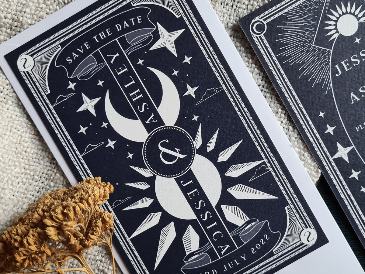 Luxury dark blue celestial Save the Date wedding stationery with gold foil star and moon accents, styled with dramatic dried florals.