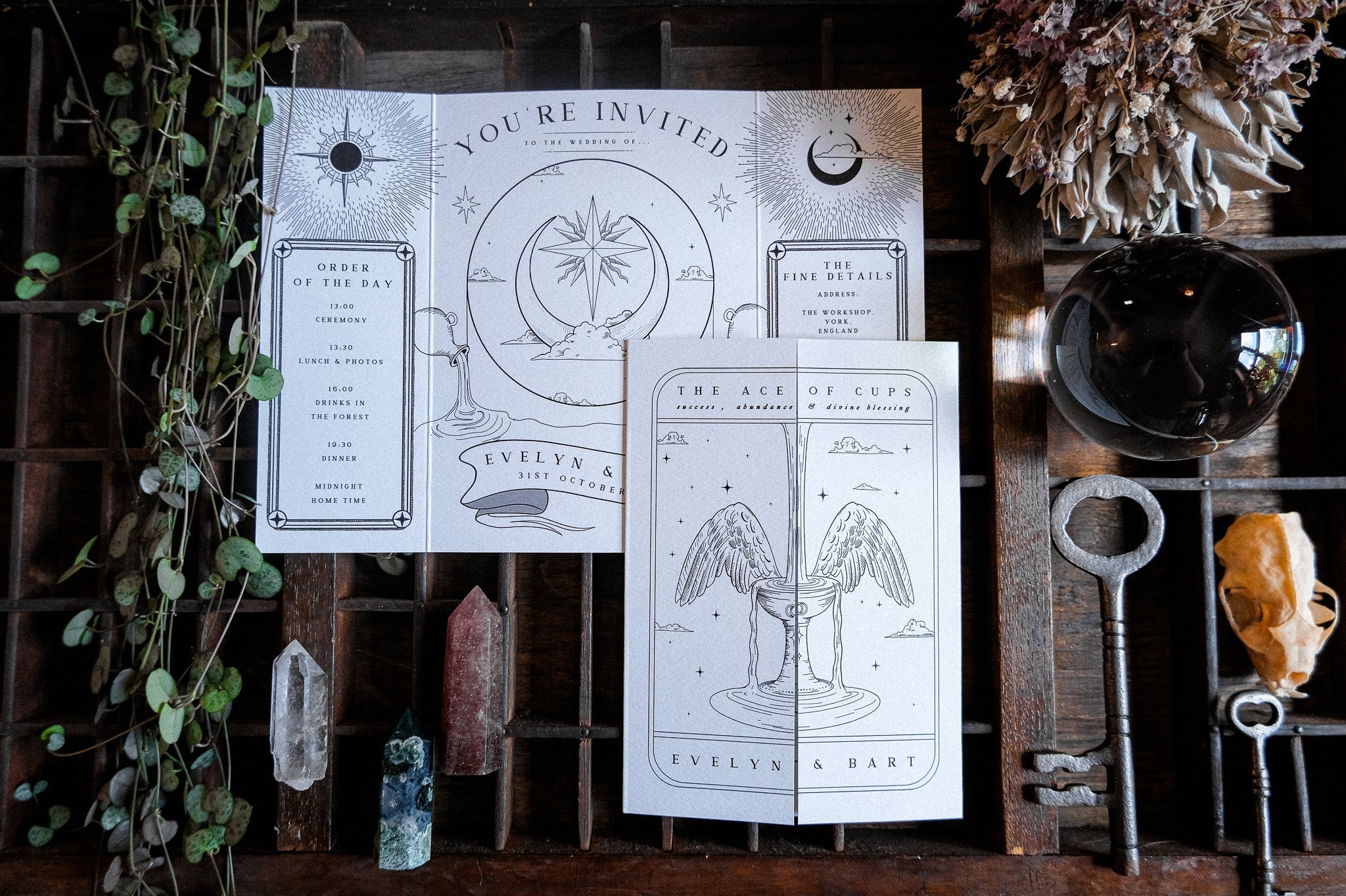 Luxury gatefold wedding invitation in a tarot-inspired celestial design, styled with crystals, dried flowers, vintage key, and vines.