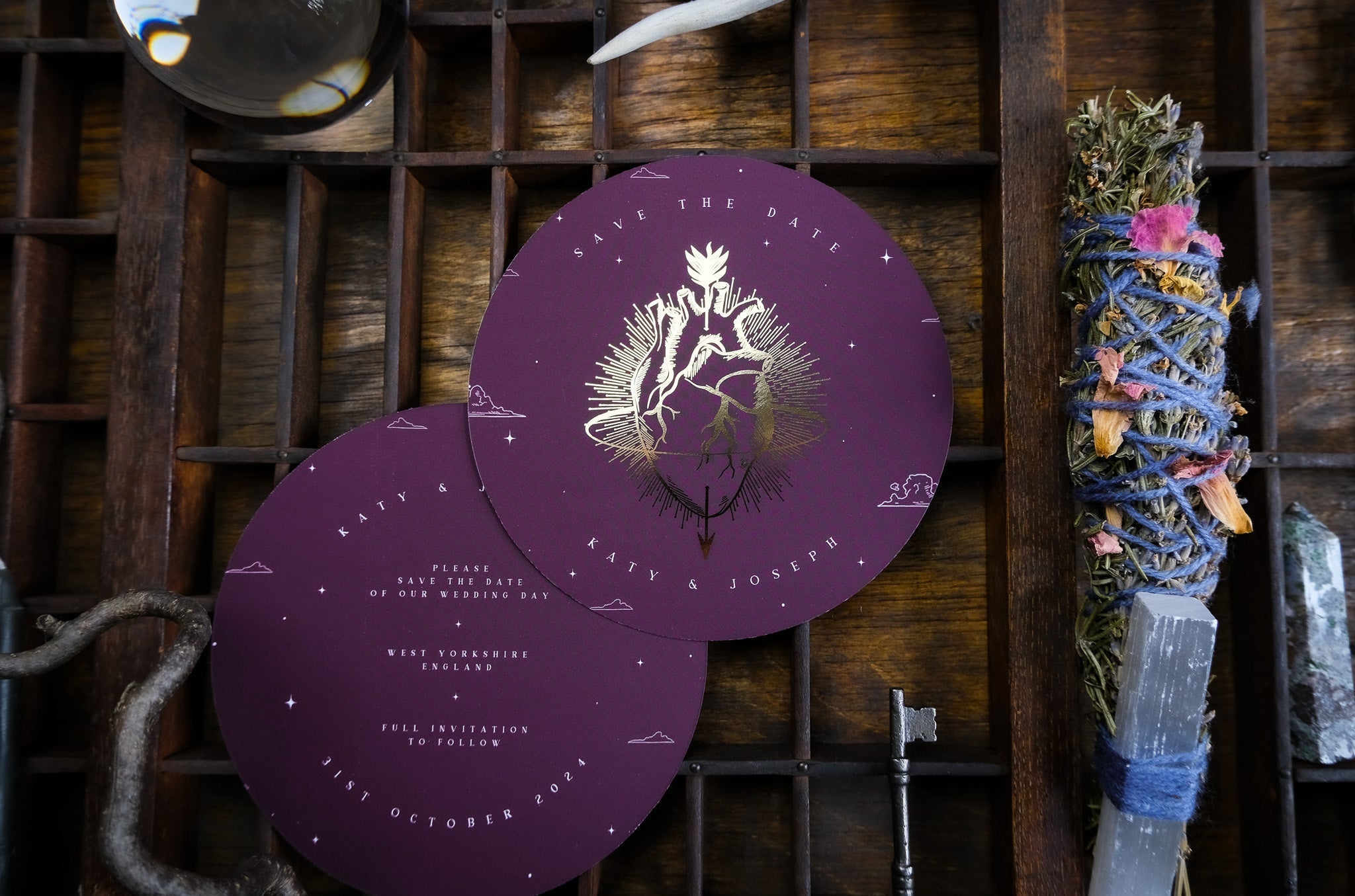 Luxury circular wedding save the date cards with gold gothic botanical foil, styled with mystical crystals, herbs, and vintage accents.