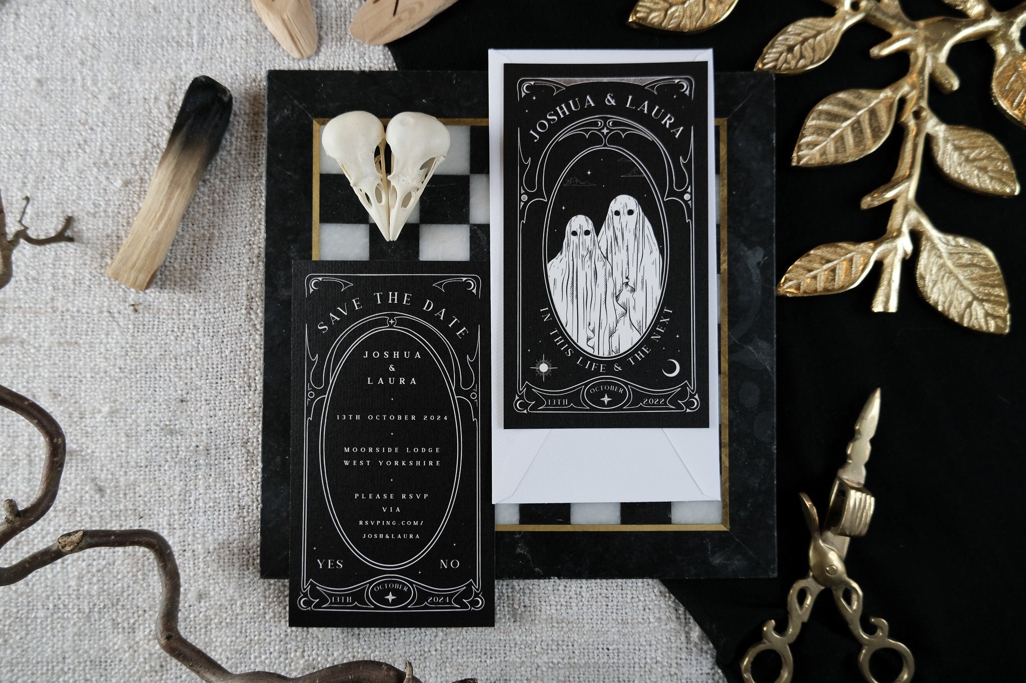 Luxury UK gothic wedding stationery suite featuring dramatic black cards, white ghost art, ornate borders, skulls, and gold foil accents.