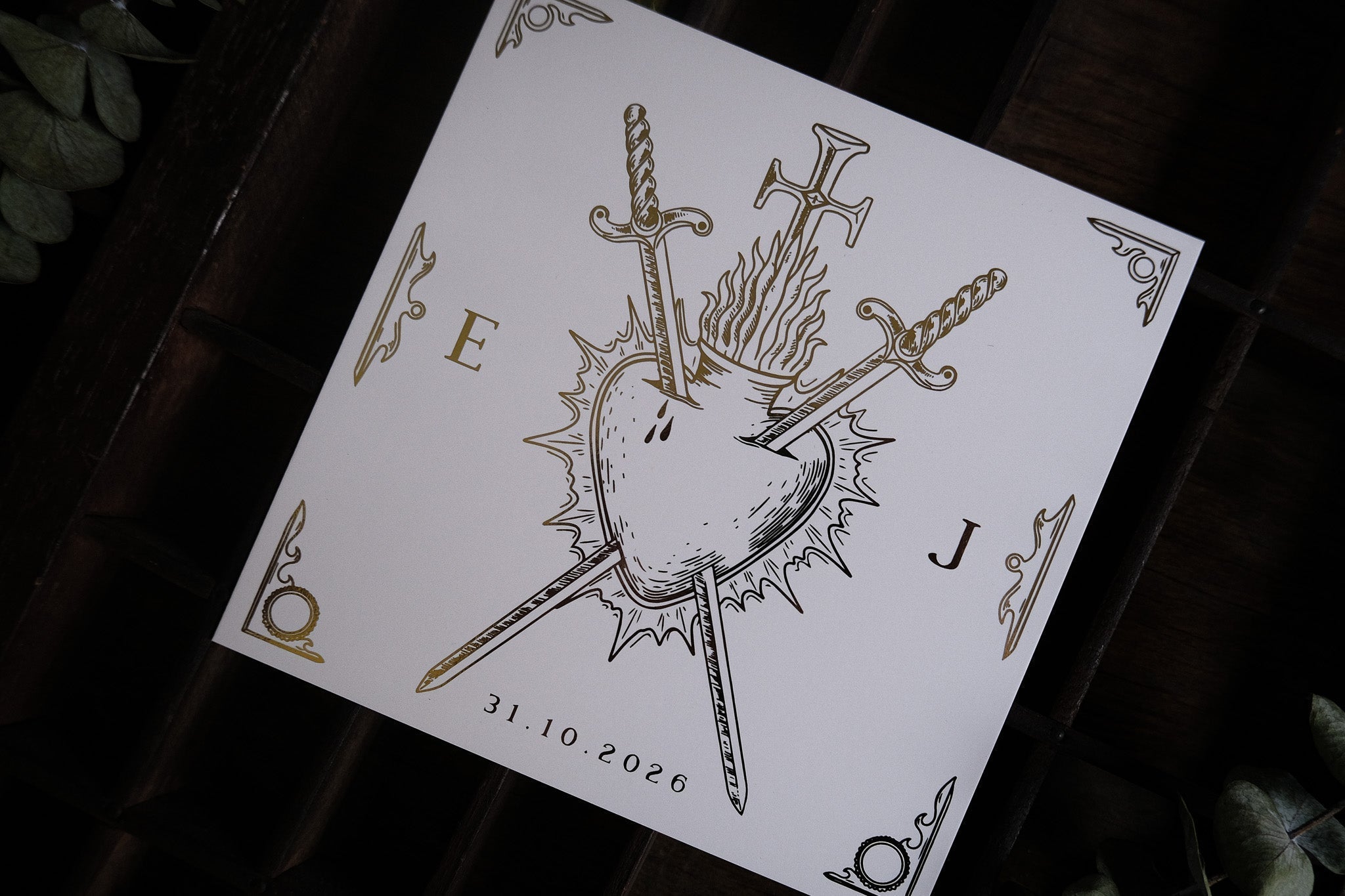 Luxury gothic save the date card with a foil-embossed bleeding heart, three swords, gold ornate corners—dramatic UK wedding stationery.