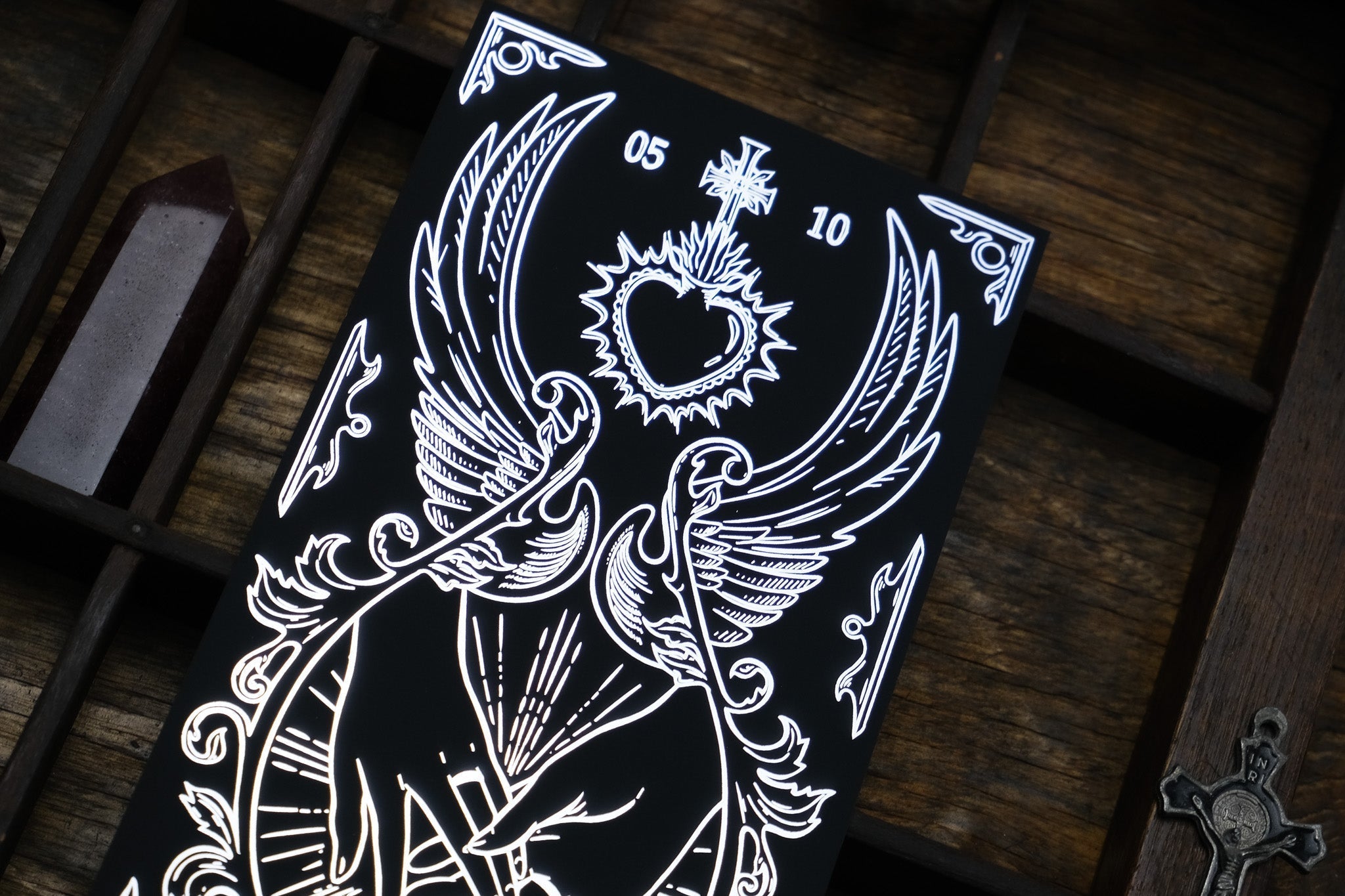Luxury UK save the date card with gothic white line art—wings, radiant heart, cross—on black, evoking romantic, mystical drama.