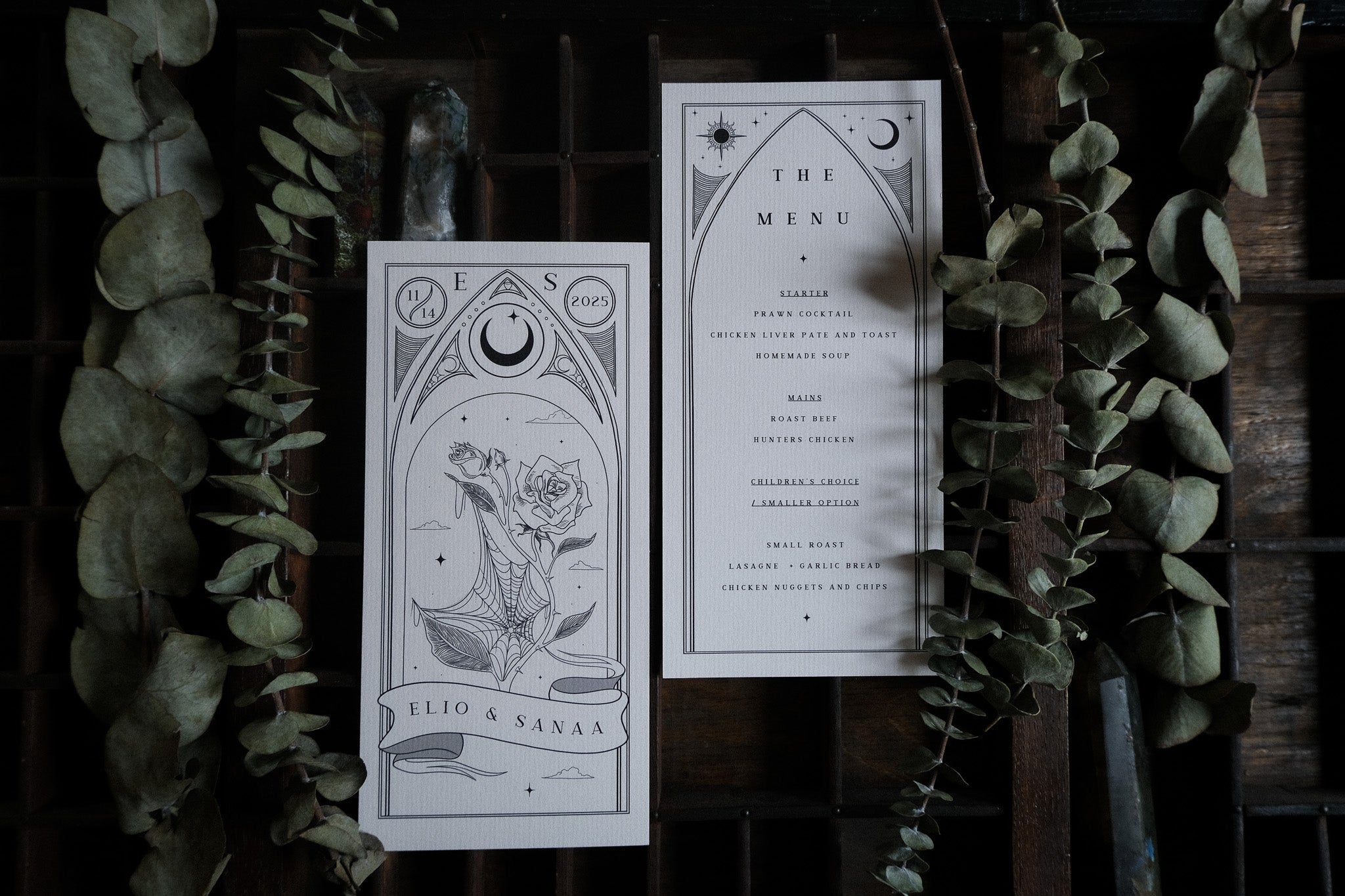 Luxury UK wedding menu cards with celestial and floral motifs, gothic romantic style, on rustic wood with eucalyptus accents.