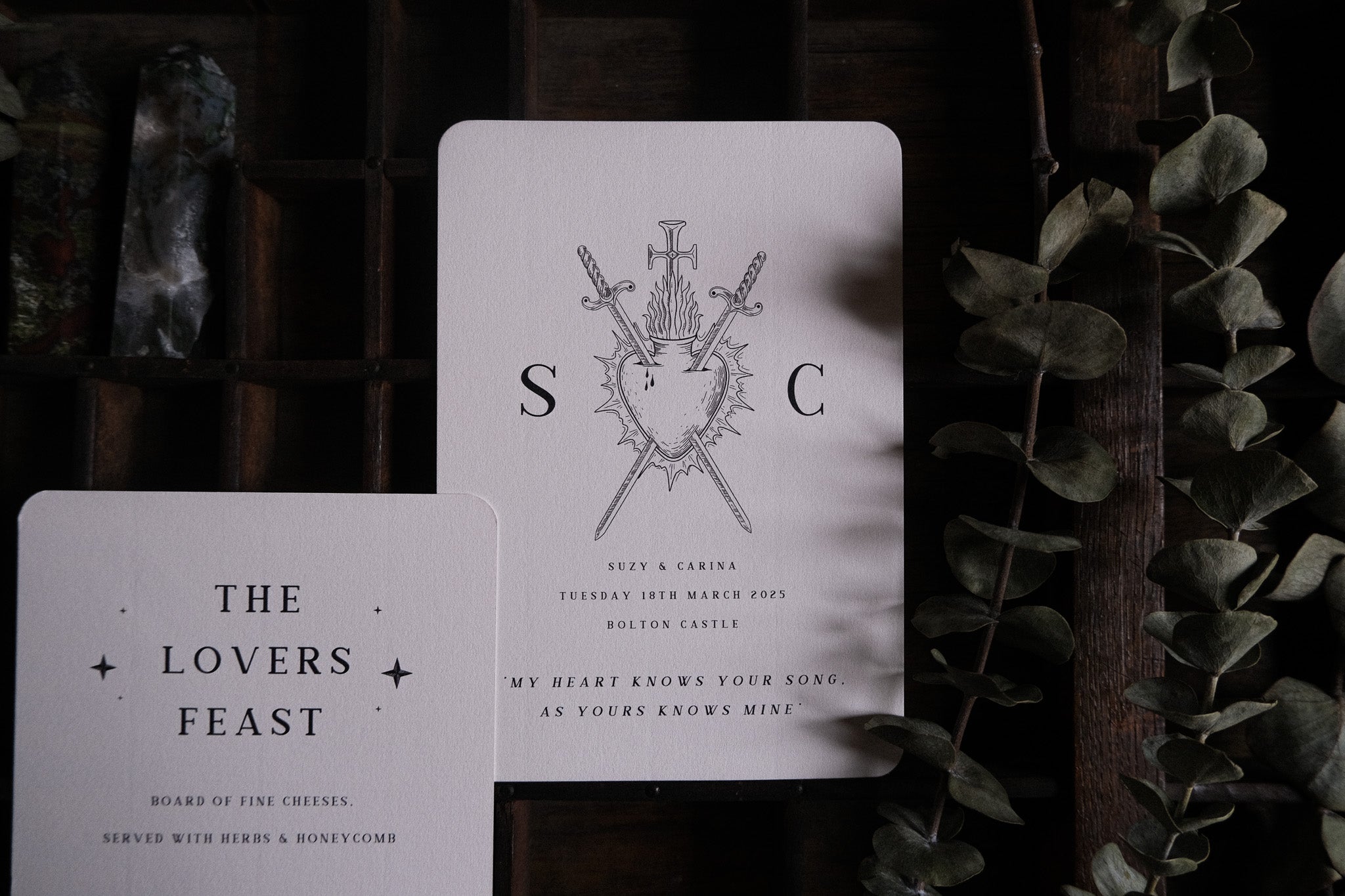 Luxury alternative wedding stationery set featuring gothic heart, swords, and arrow motifs with dramatic romantic foil accents.