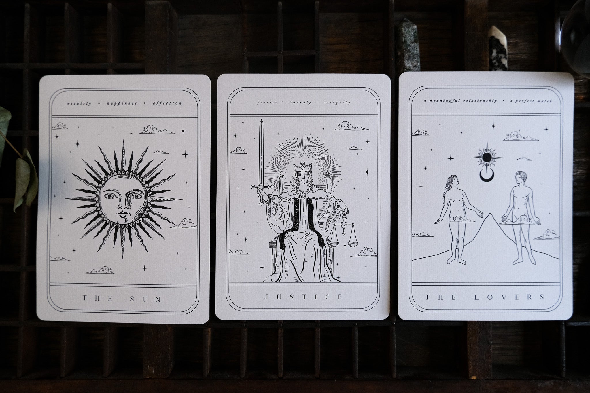 Luxury black and white tarot-style wedding stationery with mystical line art on a dark wood background, perfect for gothic UK weddings.