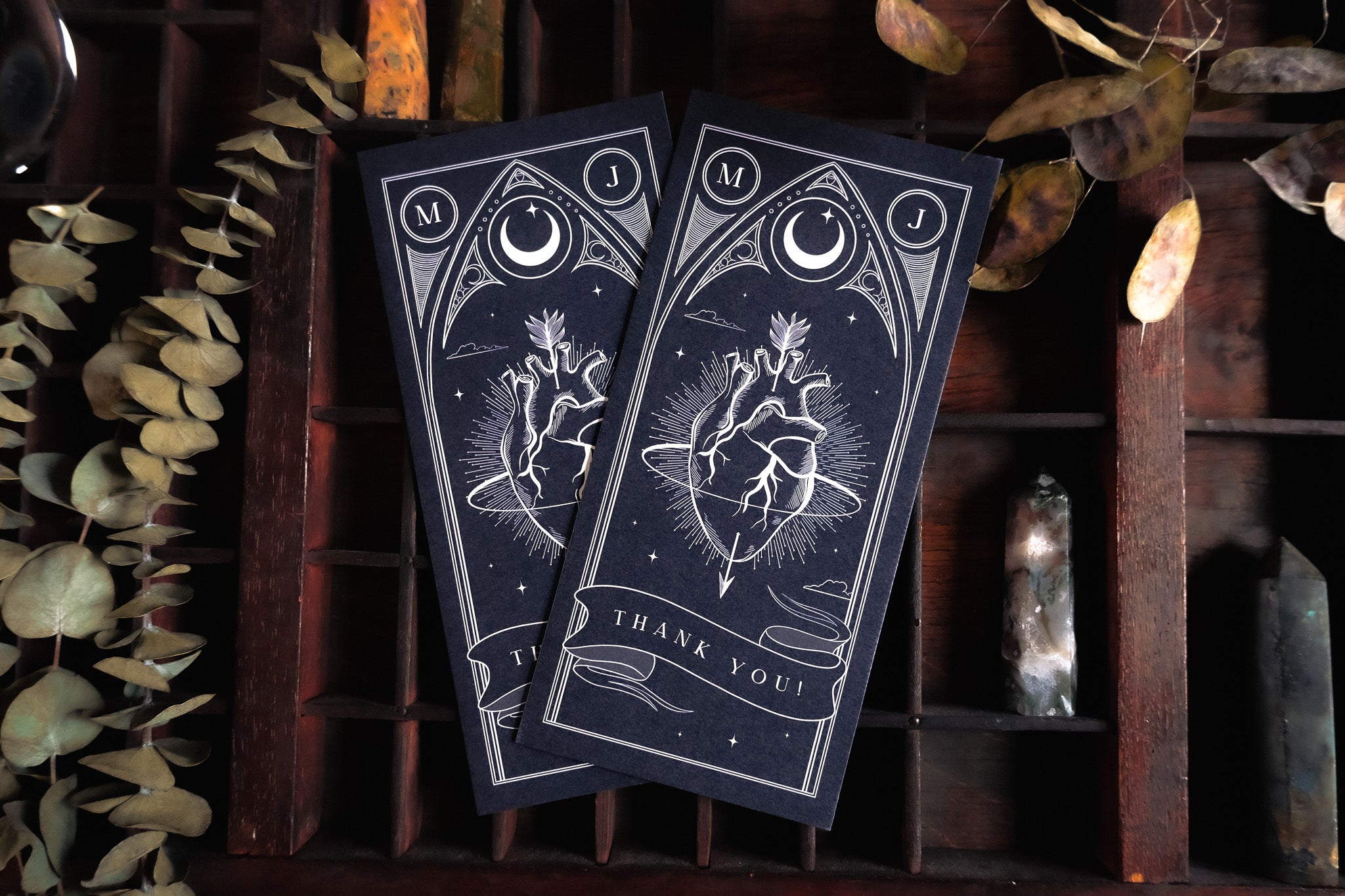 Two luxury wedding bookmarks with gothic celestial line art—anatomical heart, moon, and stars—set on dramatic dark backgrounds.