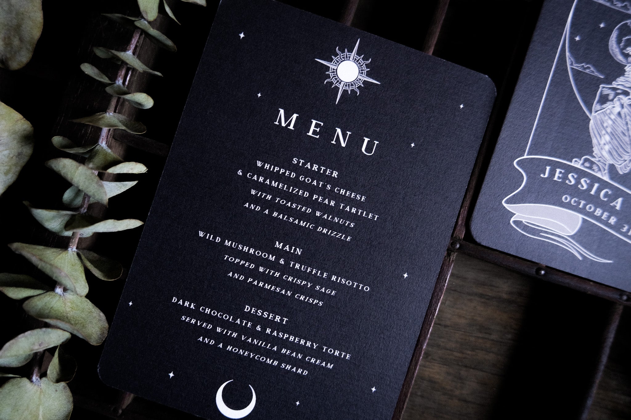 Premium UK wedding stationery menu card with a gothic skeleton couple, celestial accents, and boho details; set with dried leaves.