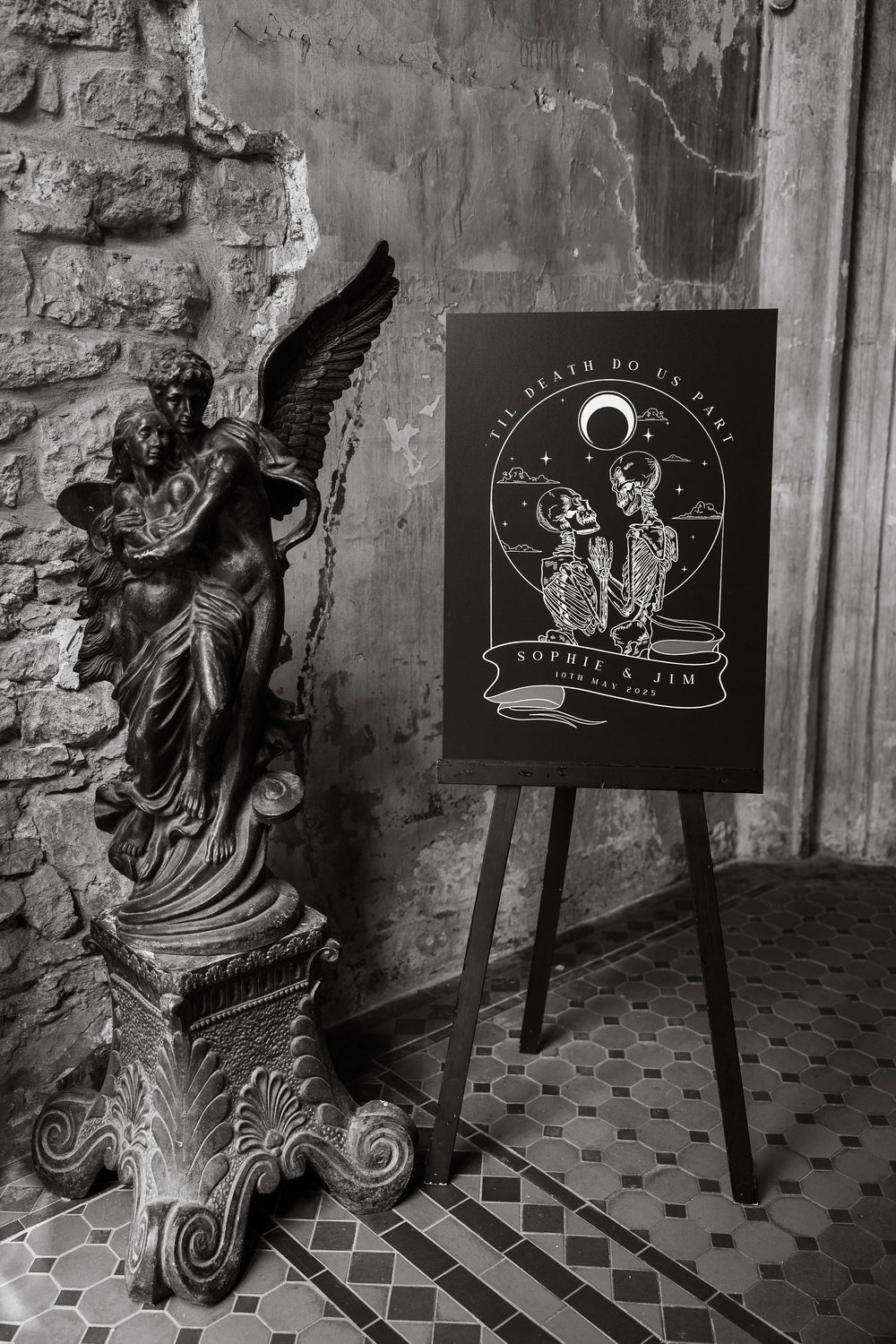 Gothic tarot style wedding welcome sign with skeletons displayed beside an angel statue