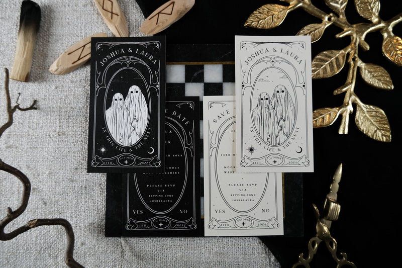 Luxury gothic save the date card with illustrated ghosts, black checkered backdrop, gold foil leaves, wood accents, and boho branches.