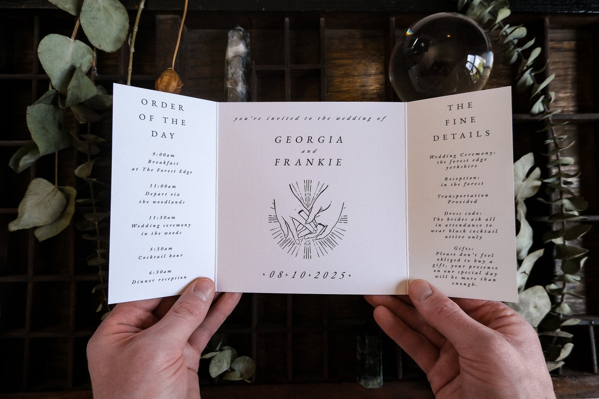 A hand displays a luxury gold foil gatefold wedding invitation with botanical accents, crafted on premium UK personalised stationery.
