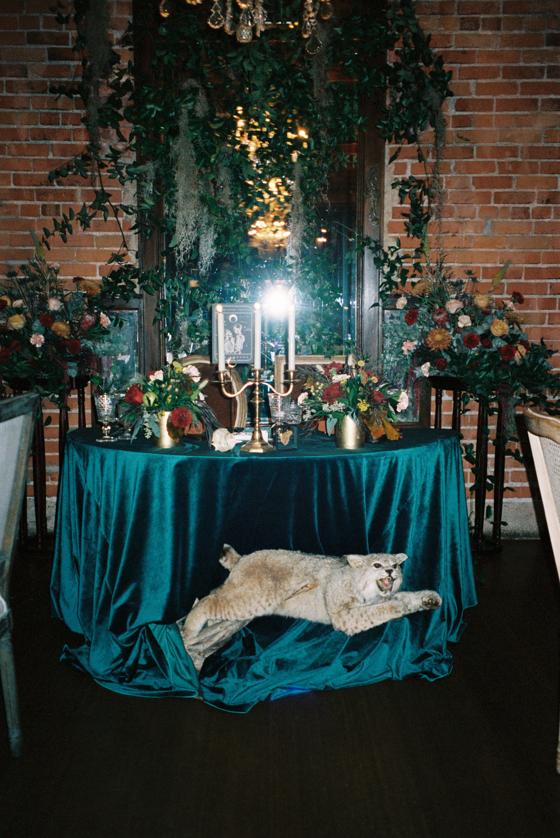 A dramatic wedding stationery set styled on emerald velvet, with candles and florals for a mystical, gothic UK luxury setting.