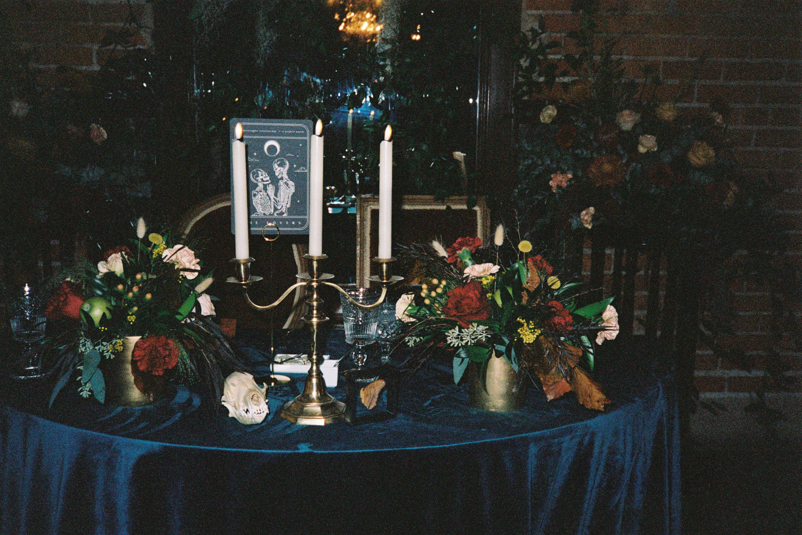 Luxury UK wedding stationery with a gothic, mystical design rests on blue velvet amid tarot cards, brass, and lush florals.