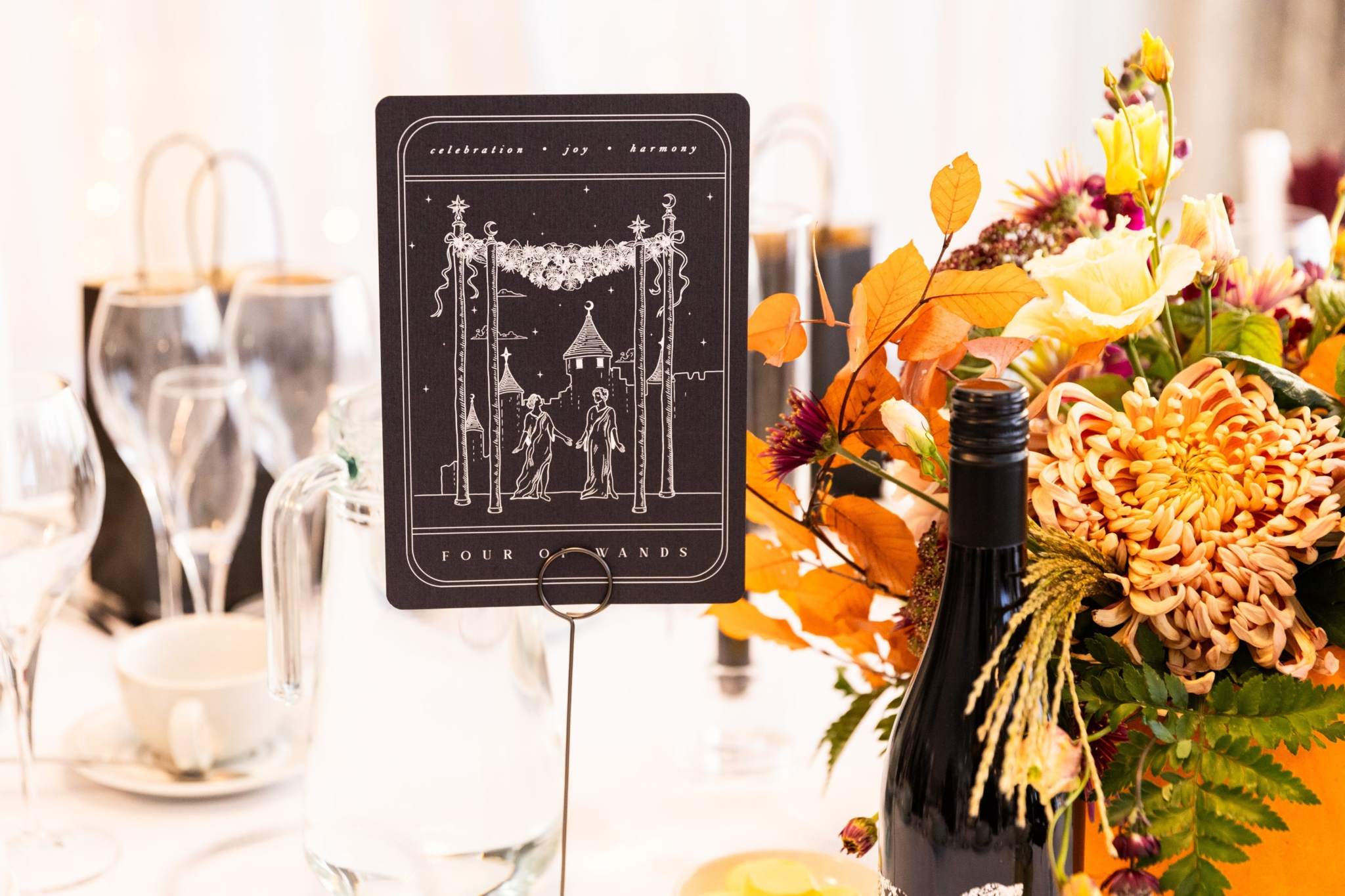 Elegant Gothic Four of Wands tarot card art print on wedding table with floral centerpiece and glassware