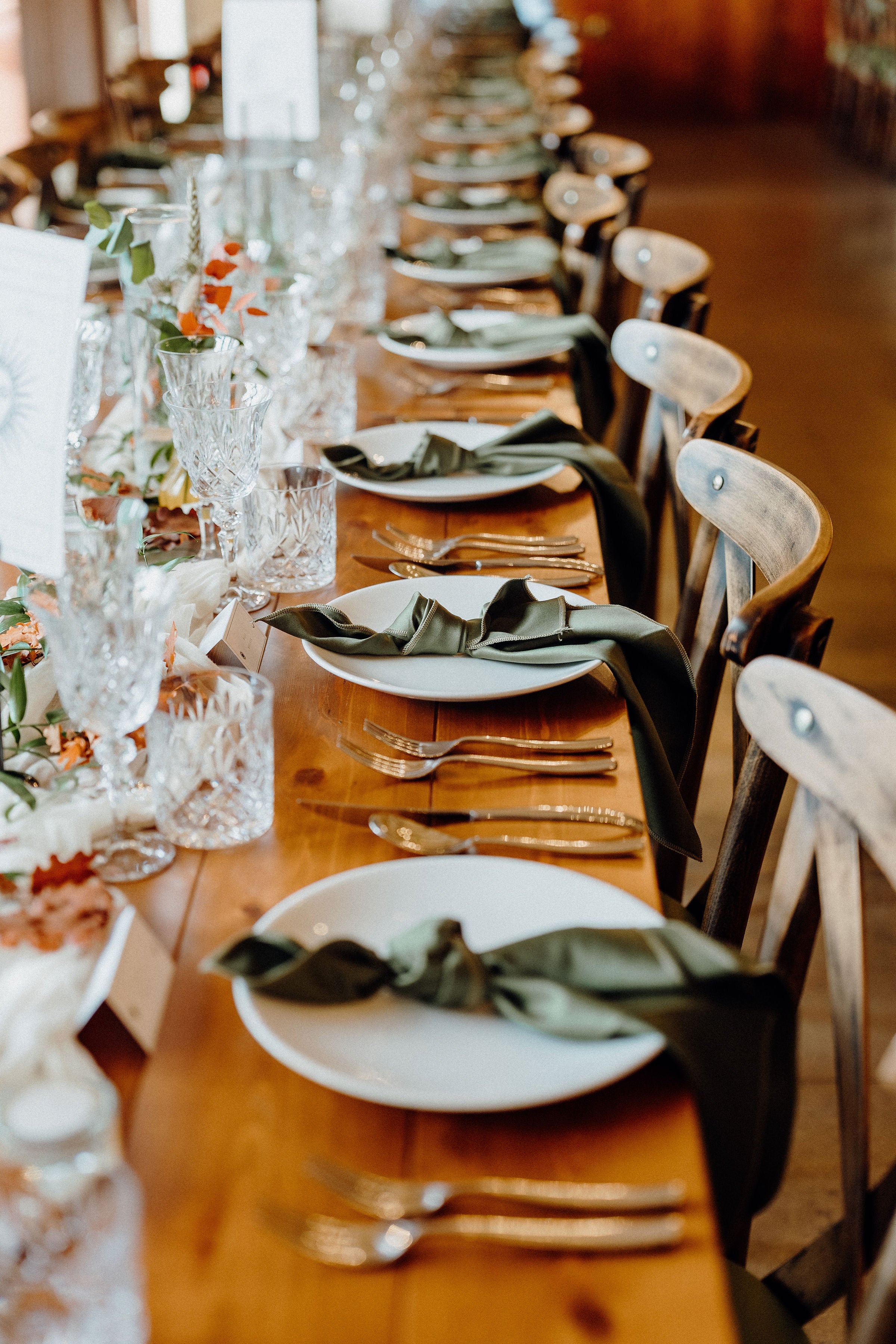 Luxury UK wedding stationery with romantic design placed on a long wooden table, set with crystal glassware and floral décor.