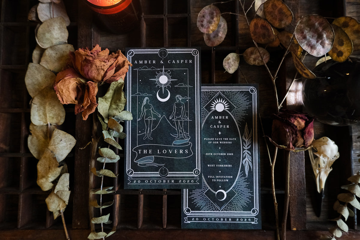 The Lovers tarot card save the date and matching card for Amber & Casper, dark green illustrated design with a sun and moon motif, styled with dried eucalyptus and roses.