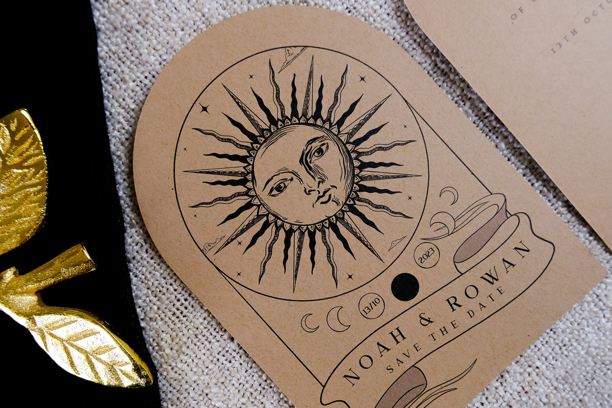 Luxury arched save the date card with mystical sun face and moon phases, gold foil accents on kraft paper, celestial boho design.