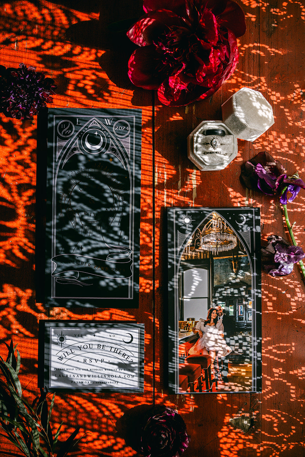 Luxury gothic wedding stationery set on wood with vintage details, red and purple florals, dramatic shadows, and personalised touches.