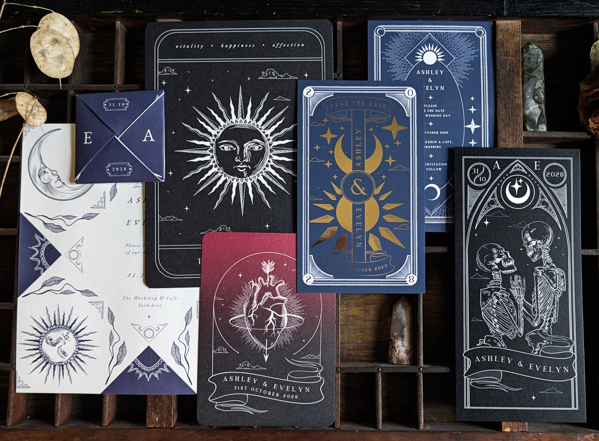 Save the date sample pack showing four gothic and celestial designs on a wooden tray